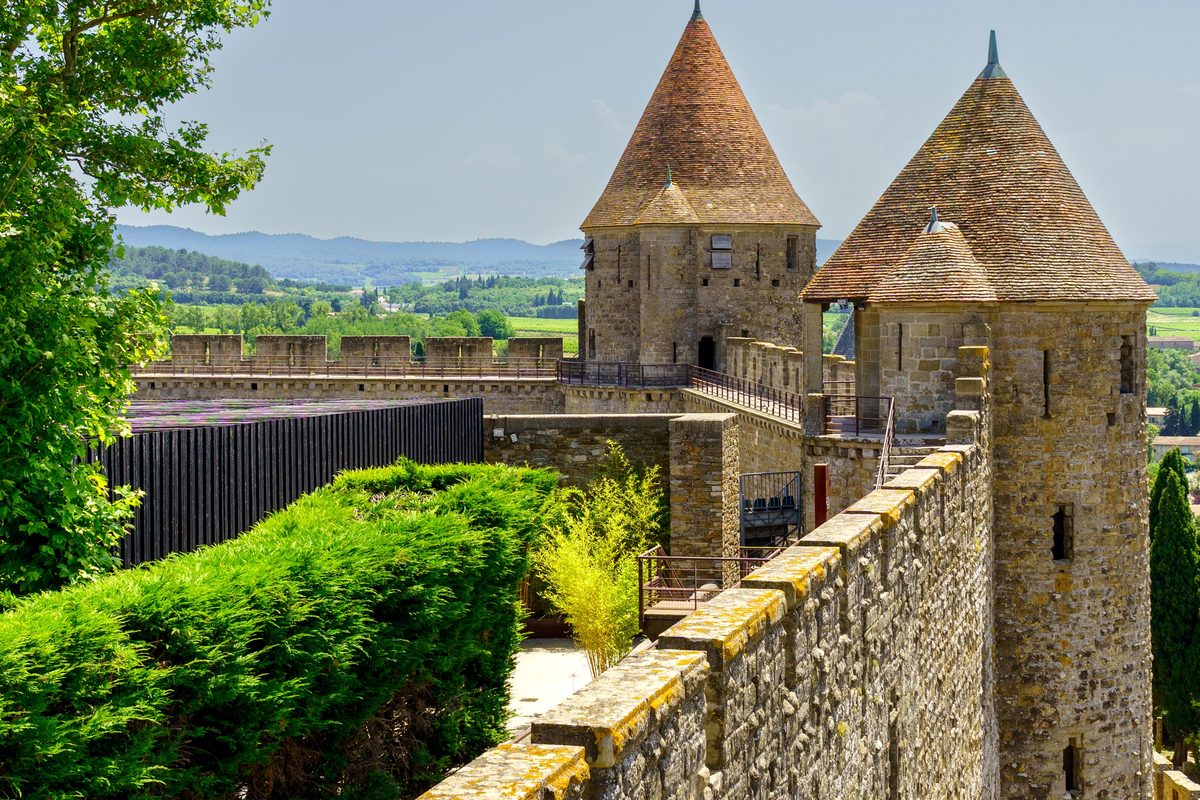 Conical-roofed towers along the ramparts of Carcassonne, a lavender field in the distance