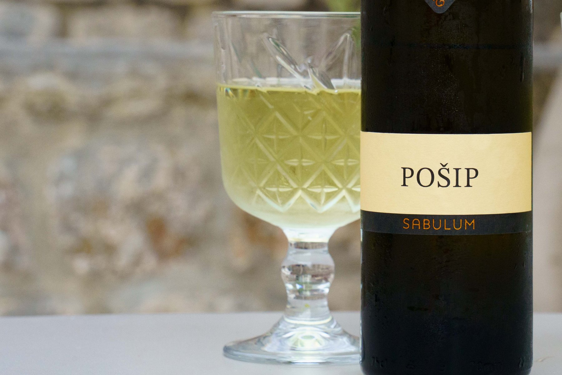 A glass of Sabulum Pošip wine enjoyed on a patio