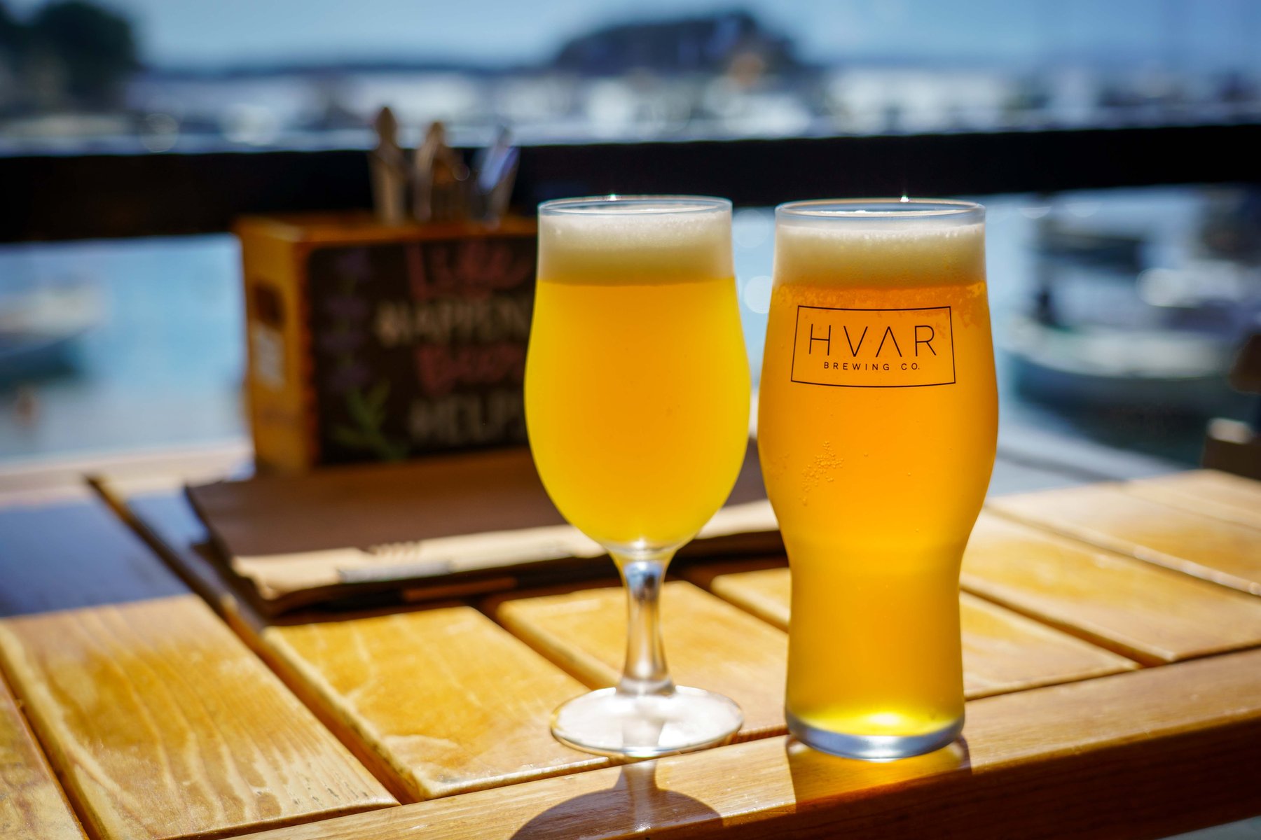 Two beers from Hvar Brewing Co. on a harborside table