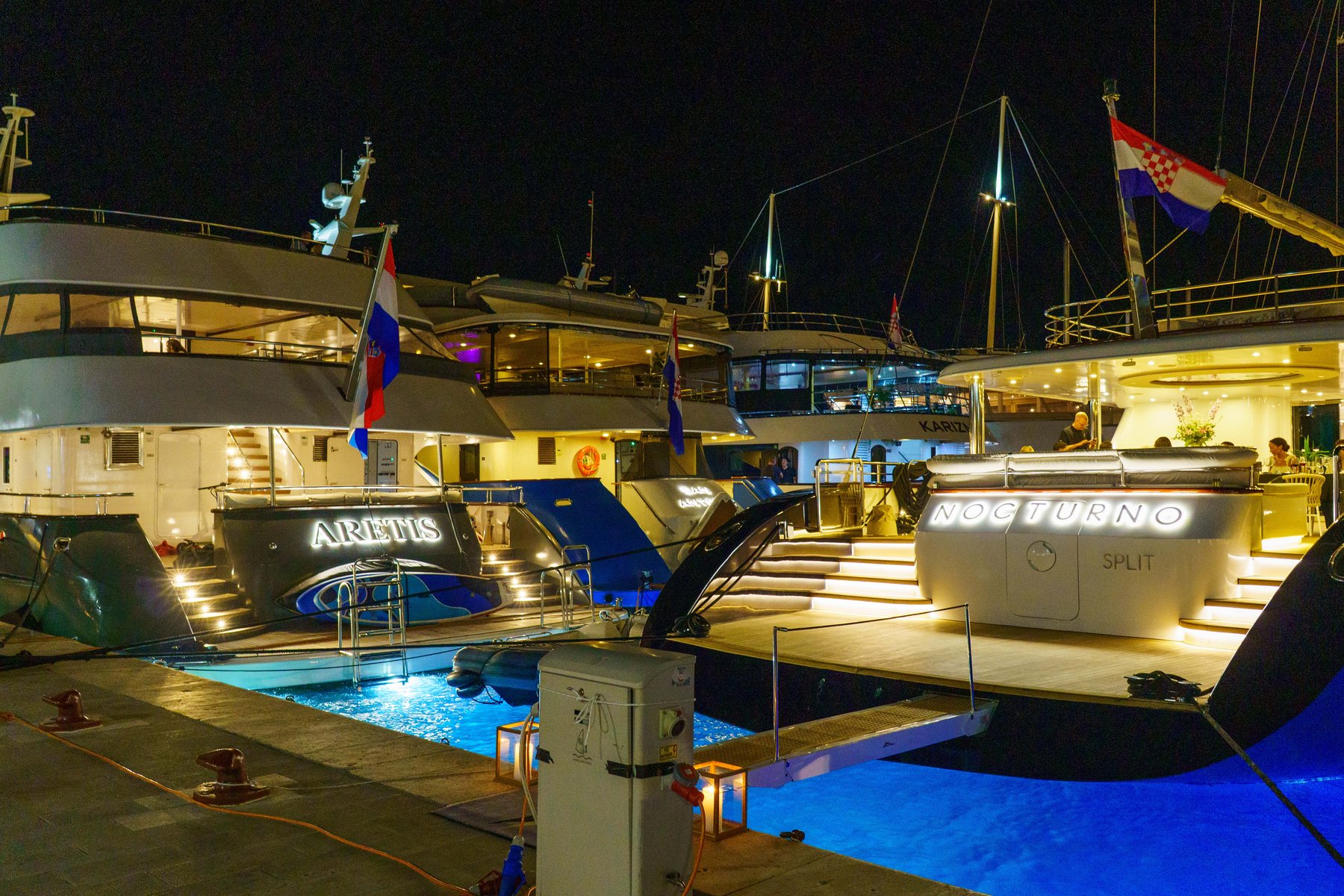 Superyachts lit up in Hvar's harbor at night