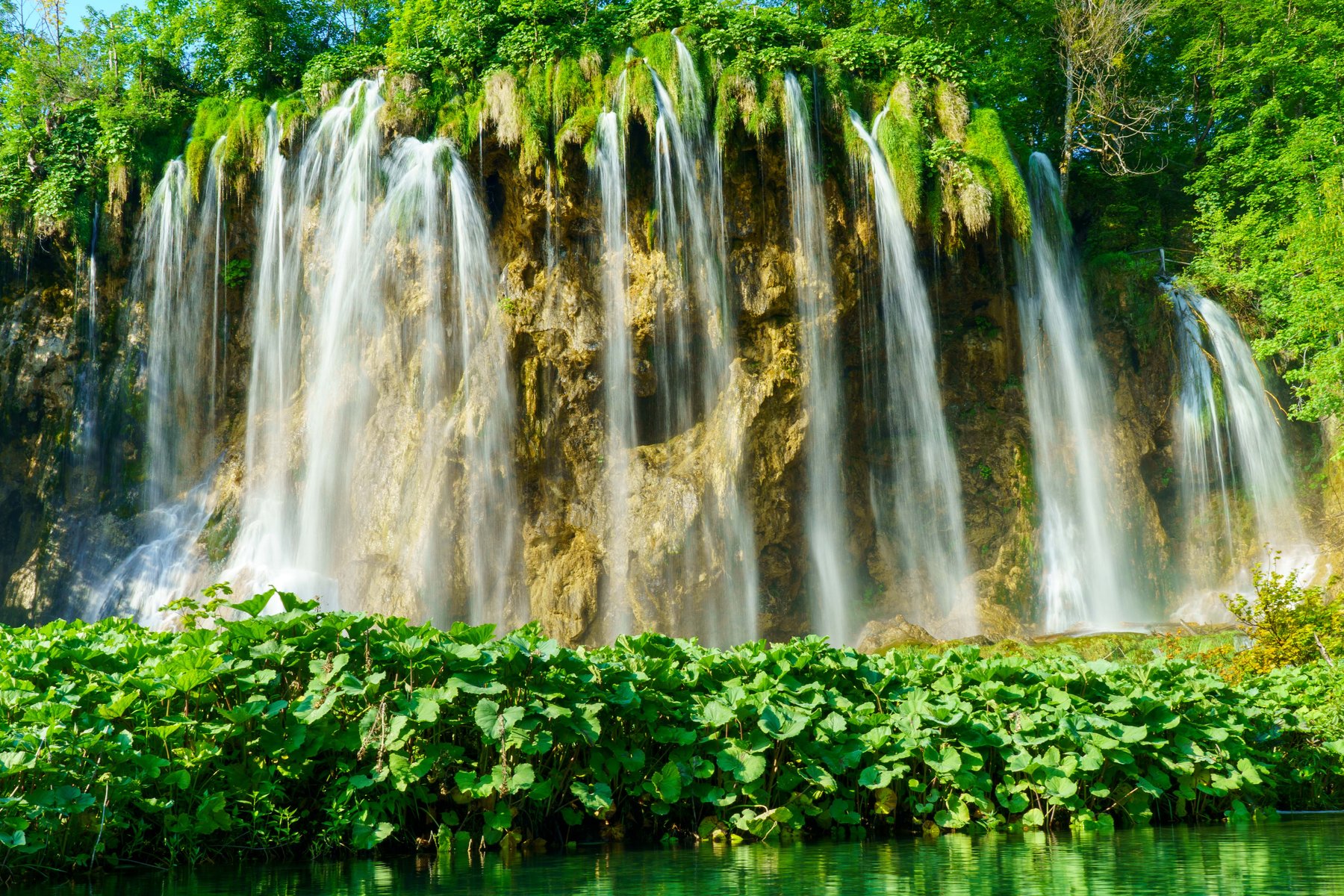 Long exposure of waterfalls cascading down a moss-covered cliff