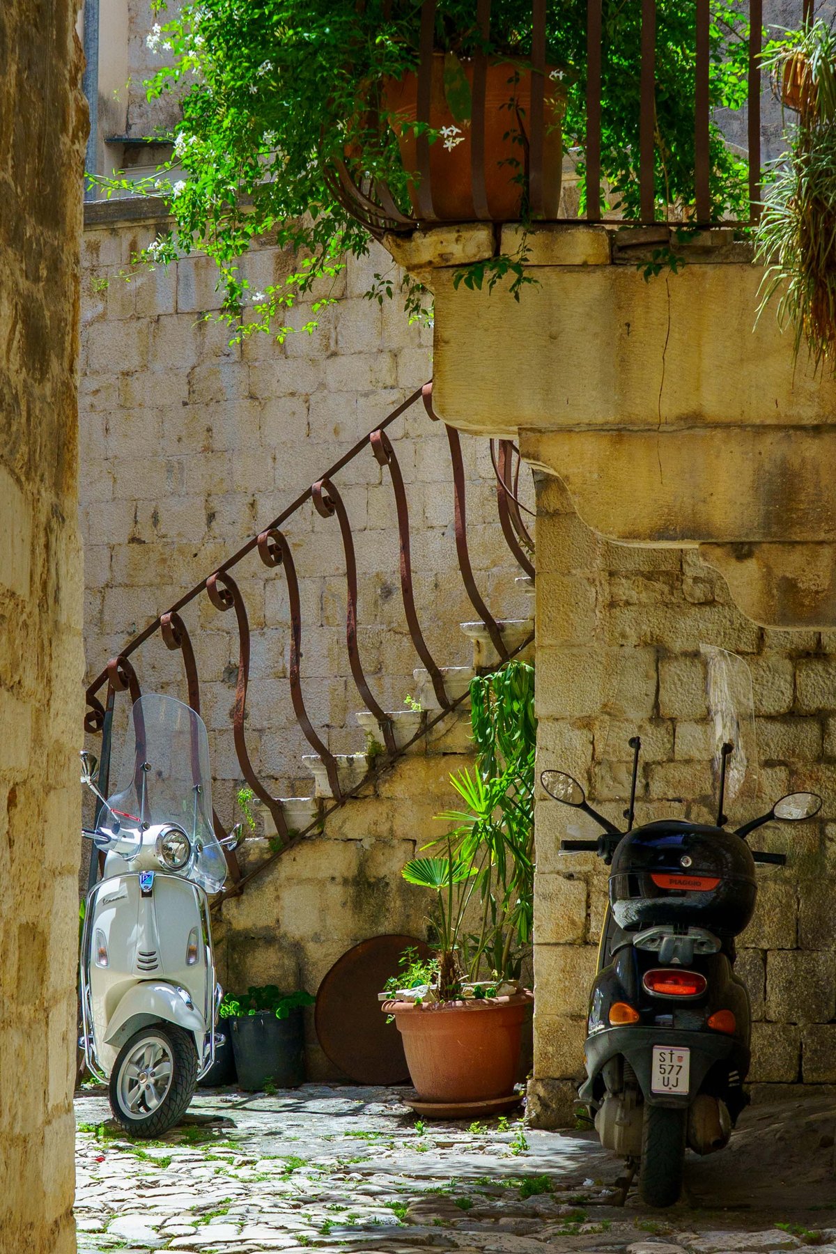 Scooters parked in a stone courtyard in Trogir