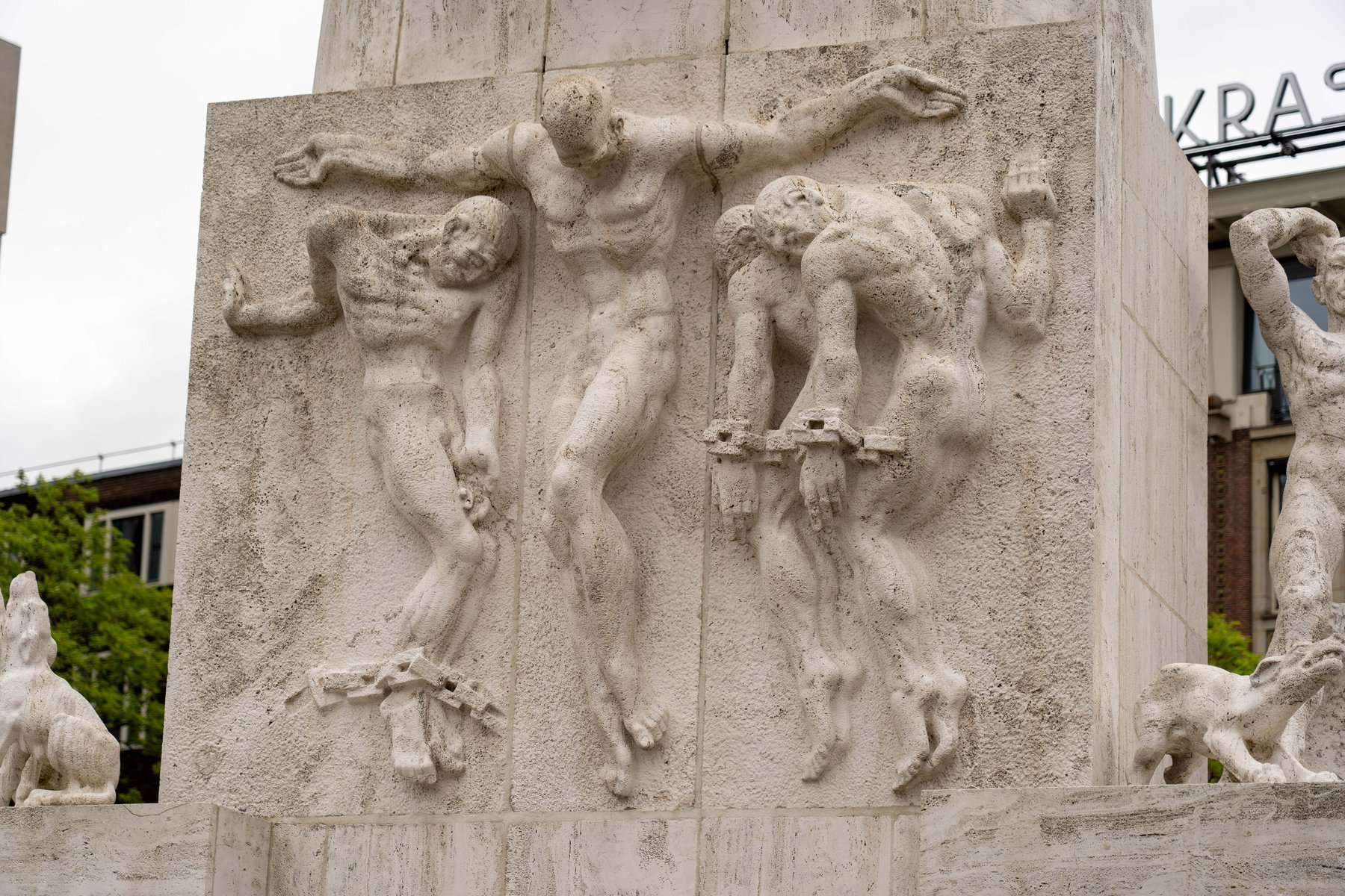 A stone relief of chained figures on the National Monument at Dam Square