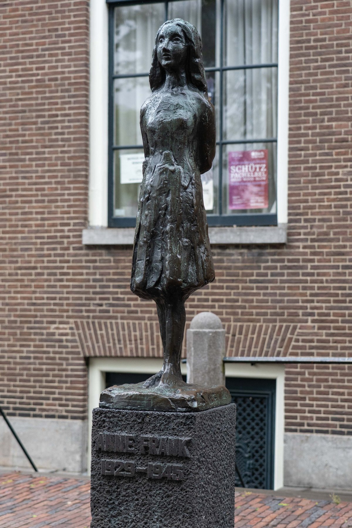 A bronze statue of Anne Frank standing near the Westerkerk