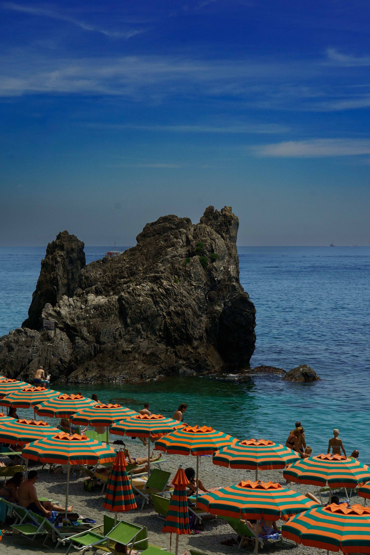 Rows of beach umbrellas beside a sea stack at Monterosso al Mare