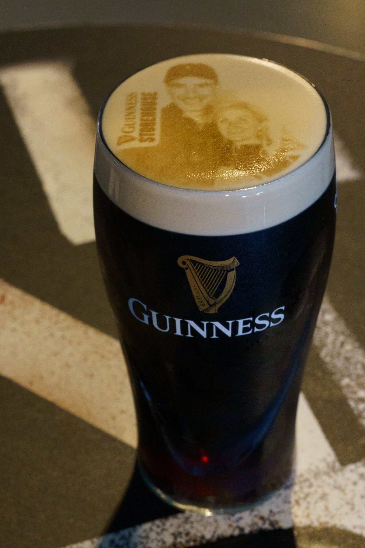 A pint of Guinness with a personalized photo portrait poured into the foam, known as a Stoutie