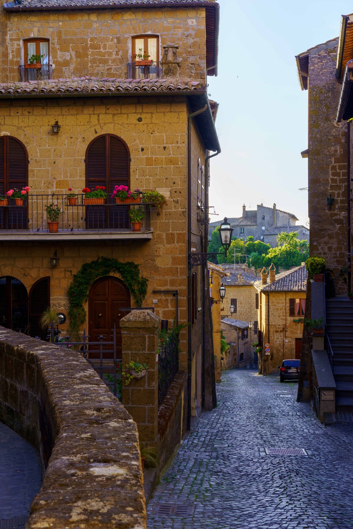 A golden stone street in Orvieto lined with geranium-filled balconies