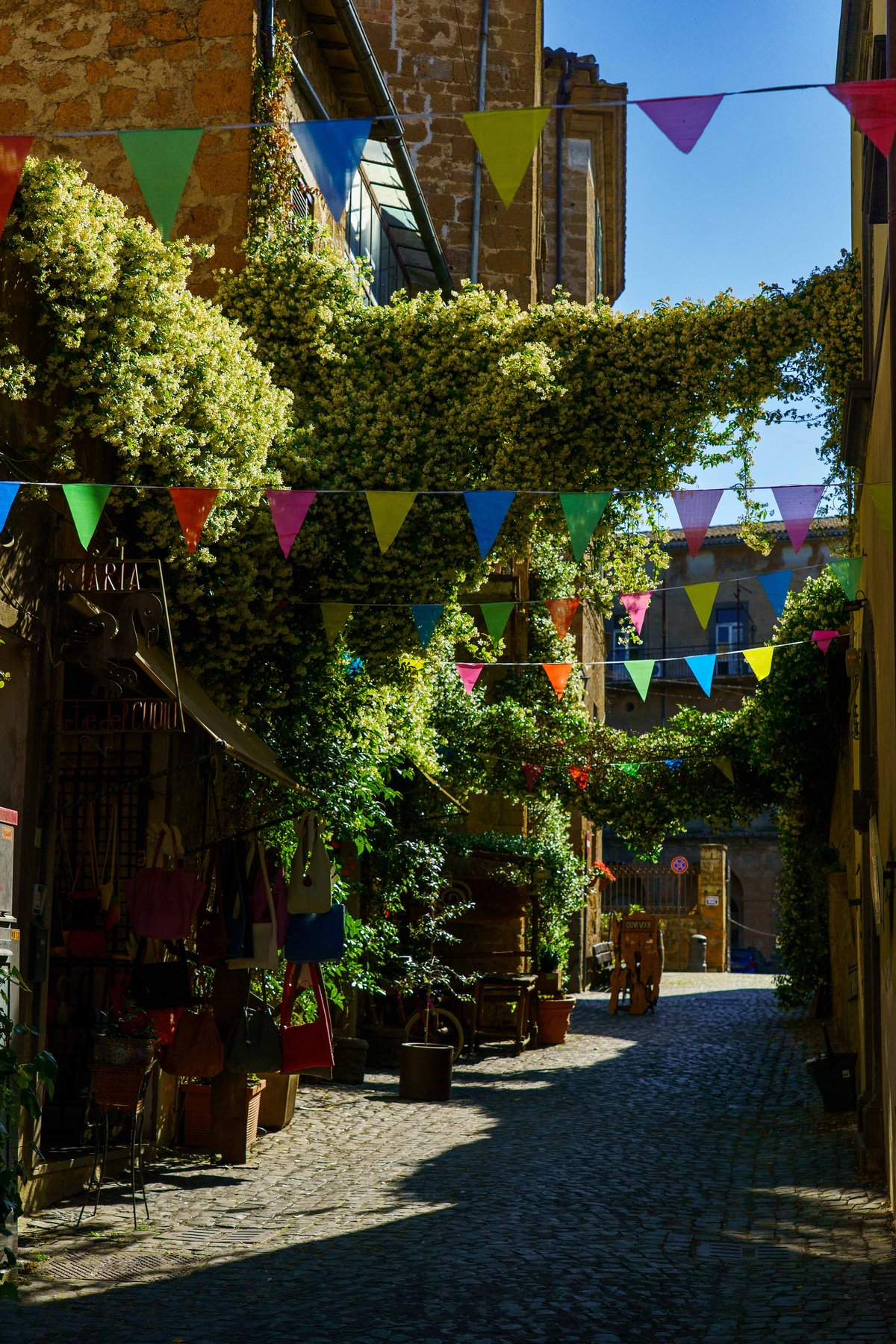An Orvieto alley strung with colorful bunting above leather goods shops