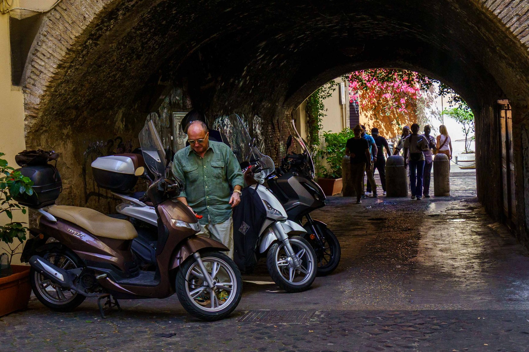 Scooters parked beneath a stone archway in Trastevere