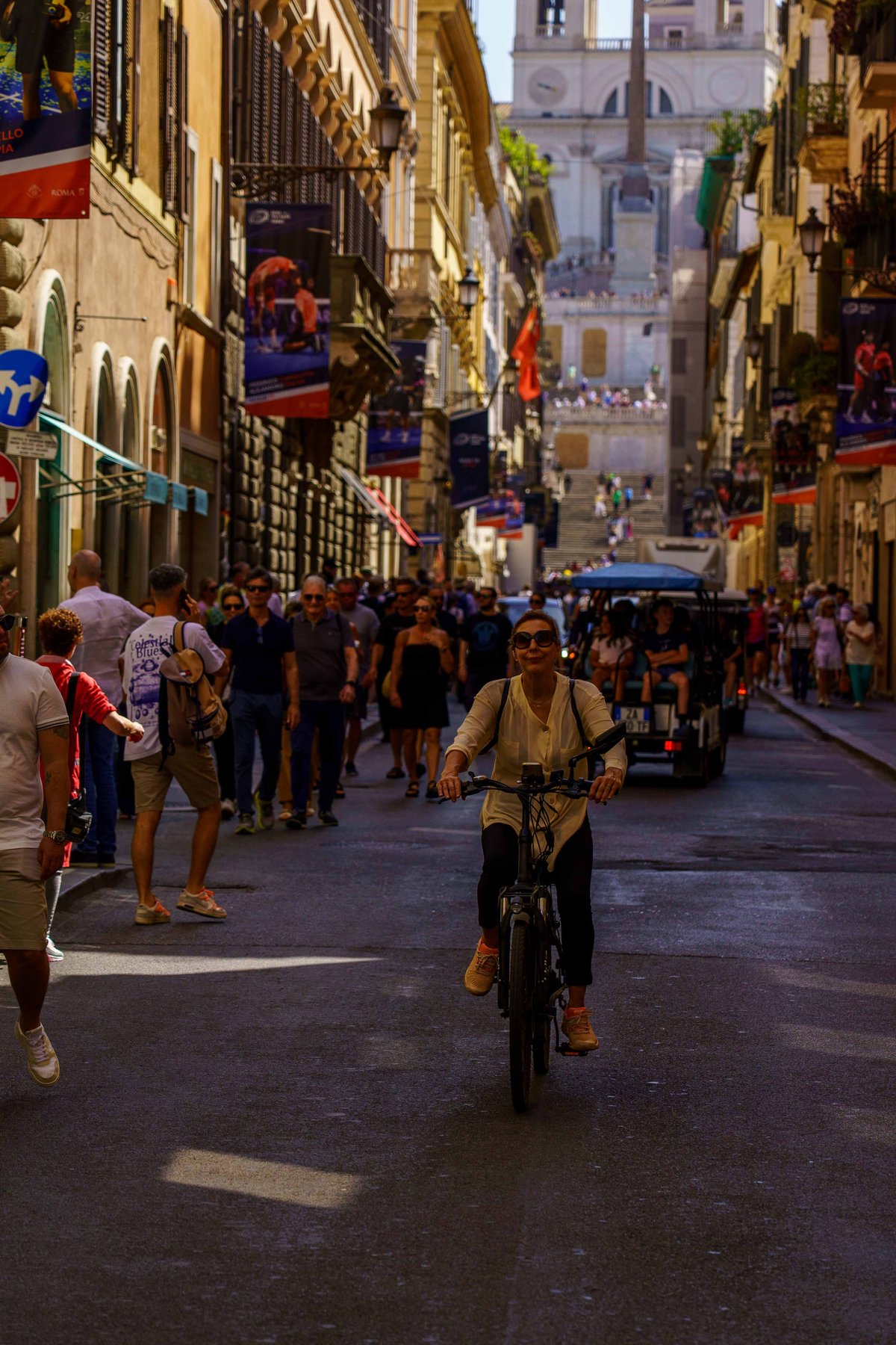 A woman cycling down a street toward the Spanish Steps