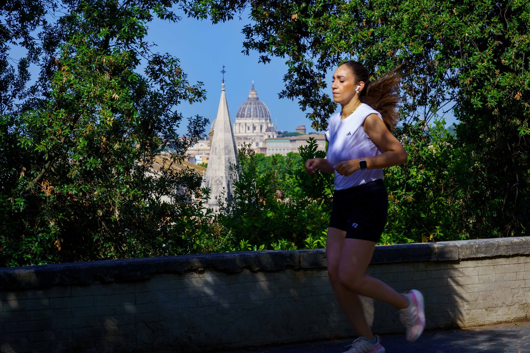 A woman running along a terrace with St. Peter's Basilica in the distance