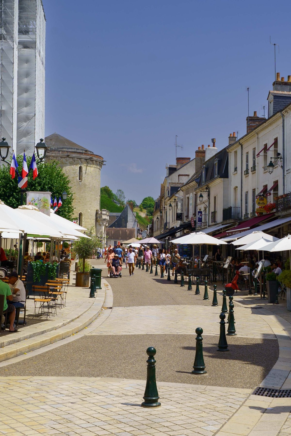 A busy pedestrian street in Amboise, the chateau's towers rising above the rooftops
