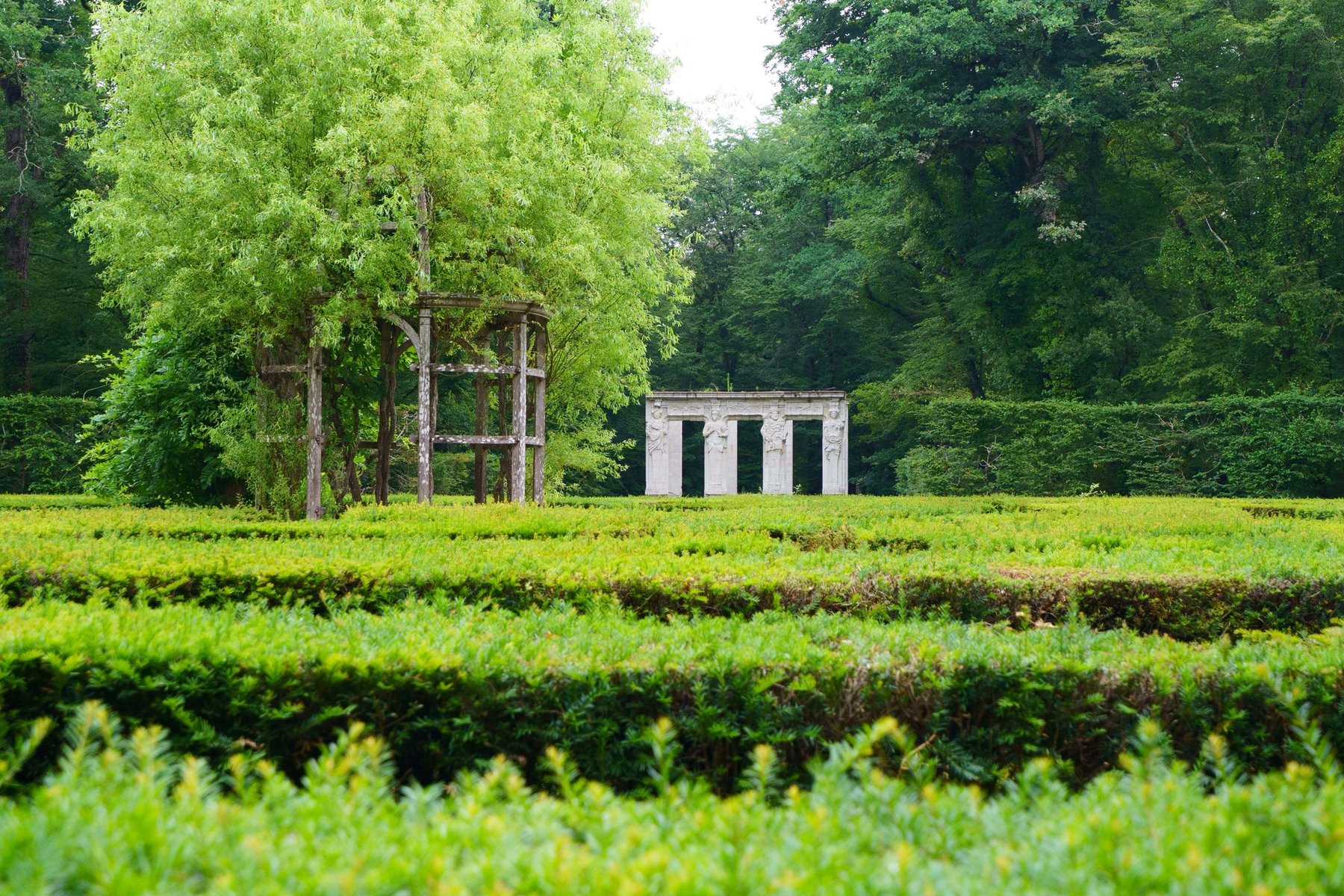 A garden pergola and stone colonnade tucked among the hedges at Chenonceau