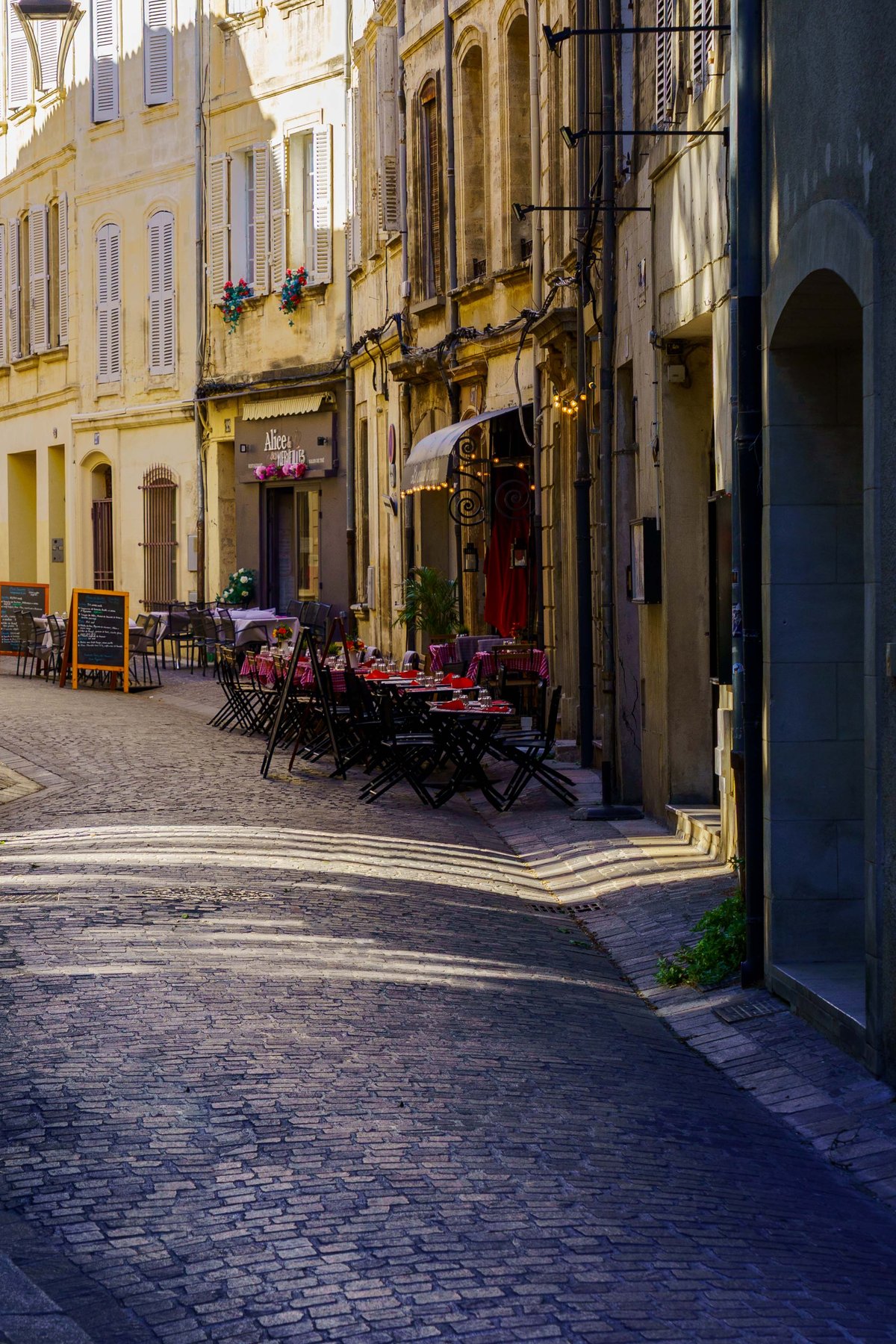 A cobblestone street lined with cafe tables in Avignon's old town