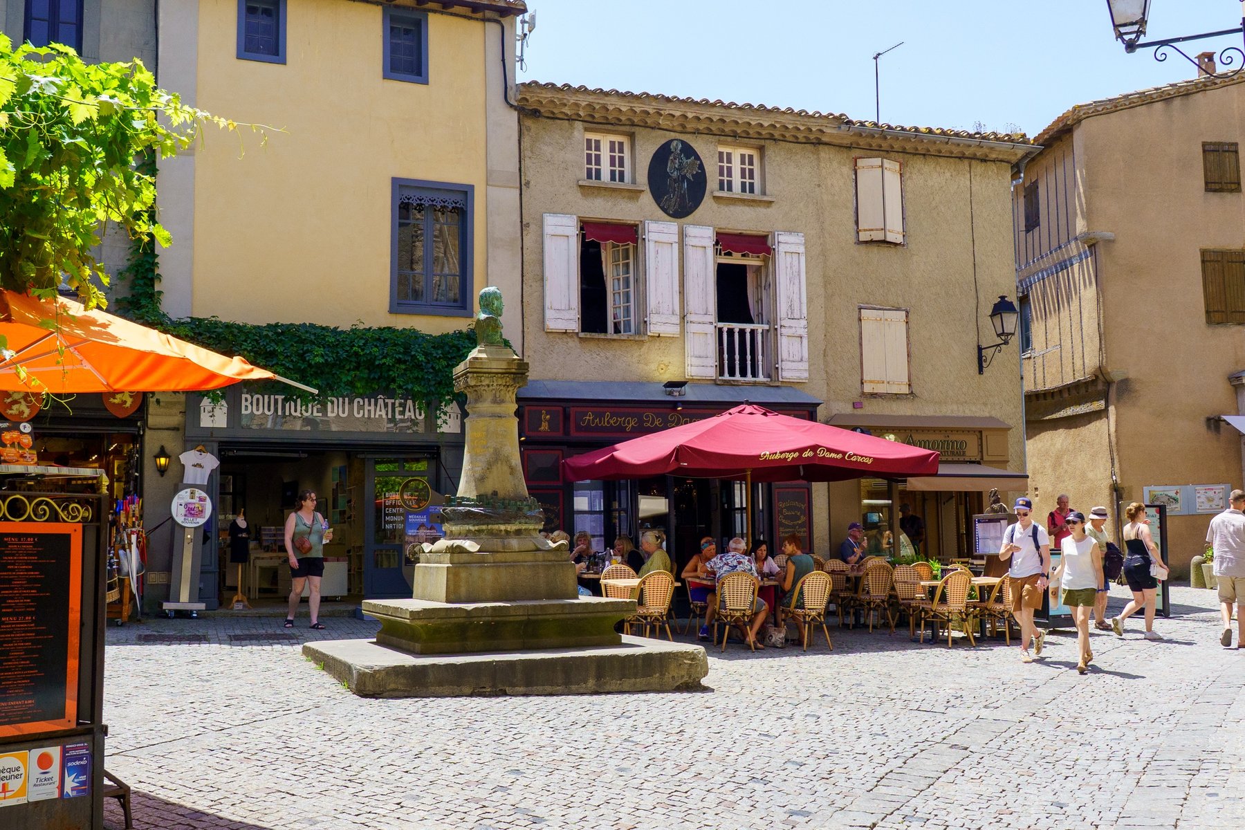 A medieval square inside the Cite de Carcassonne, tables set outside the Auberge de Dame Carcas