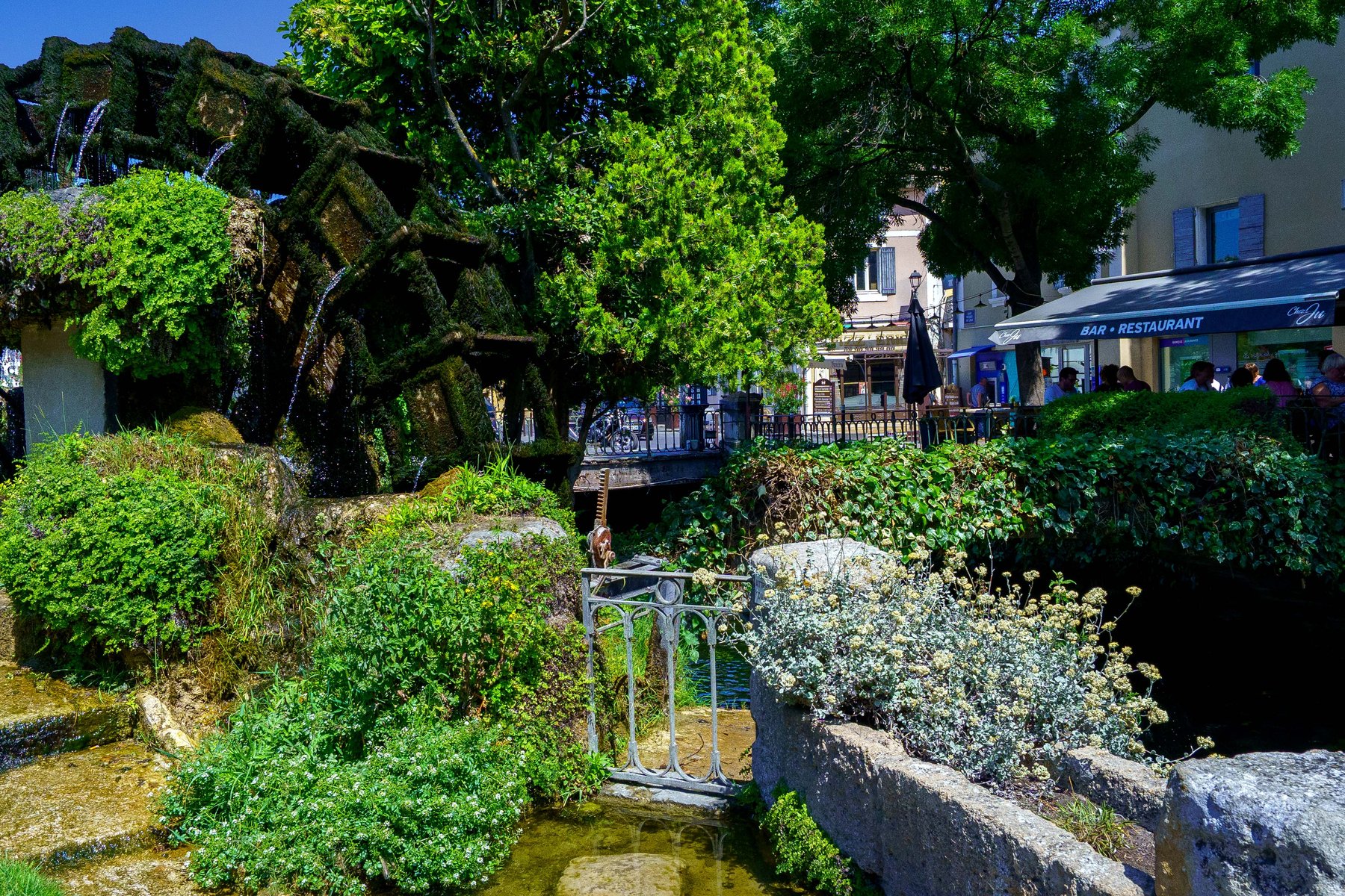 A moss-covered waterwheel turning on the Sorgue river in L'Isle-sur-la-Sorgue, France