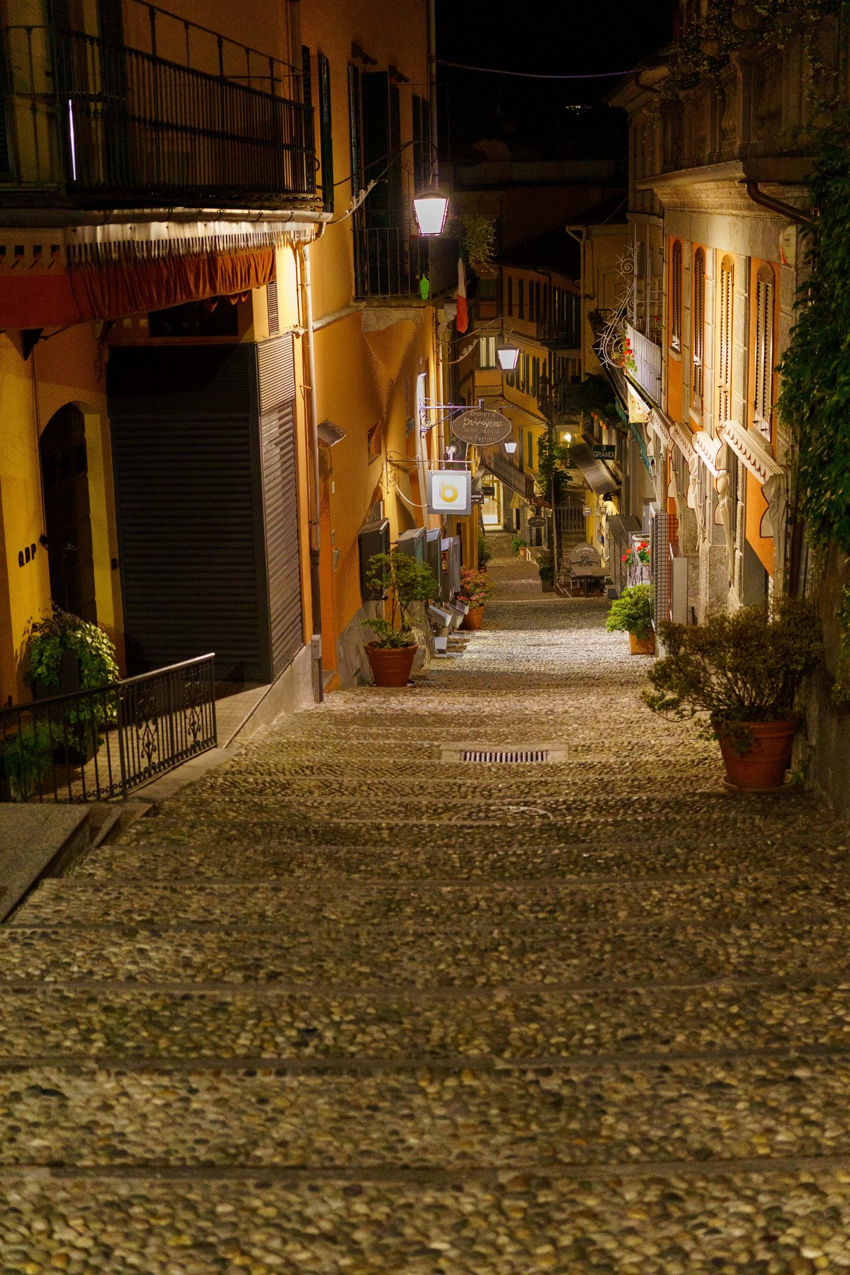 A steep cobblestone stairway street lit up at night in Bellagio