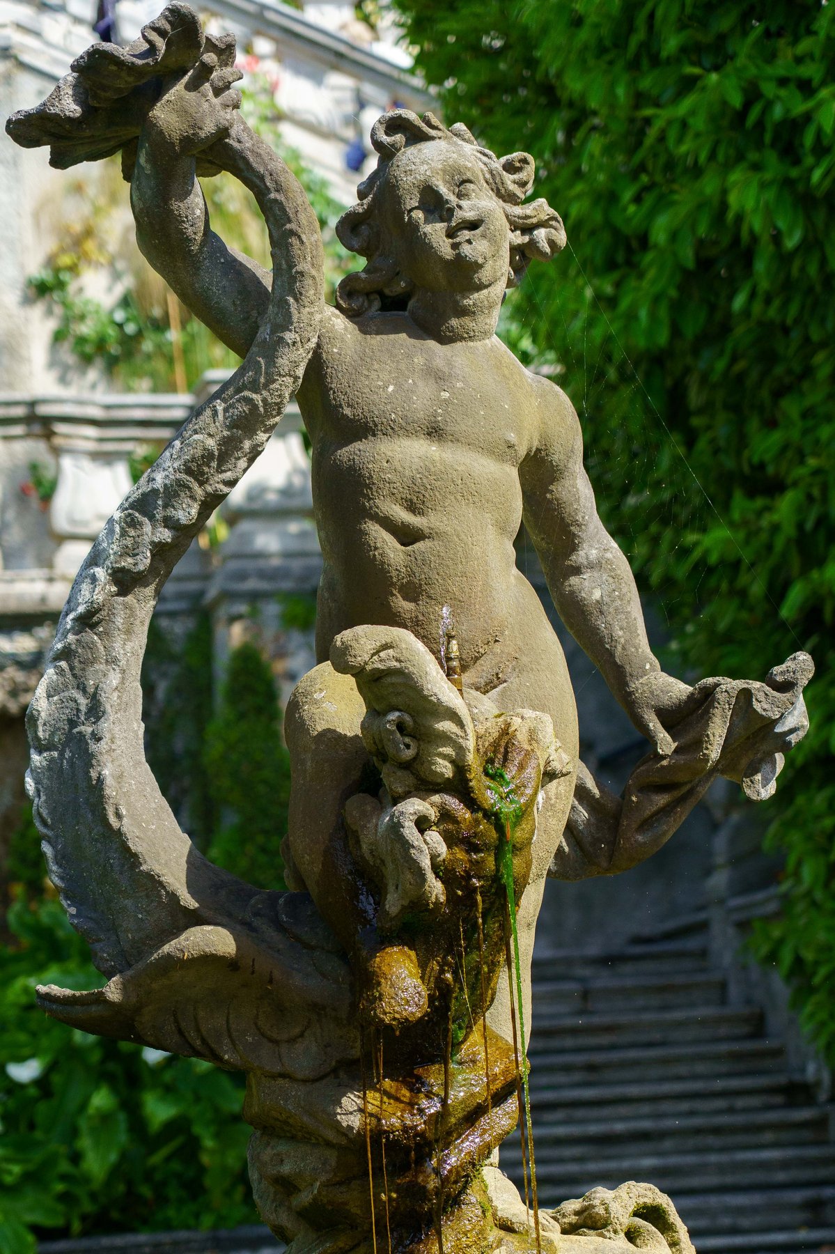 A weathered triton fountain statue in the gardens of Villa Carlotta