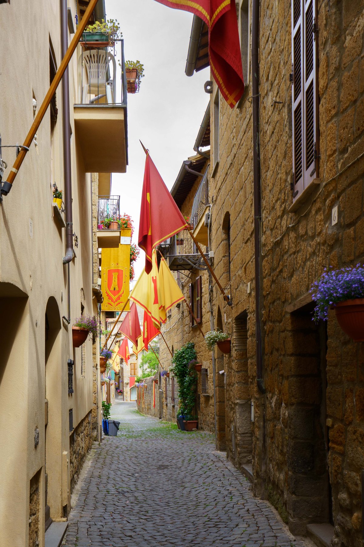 A narrow alley in Orvieto strung with medieval red and yellow banners