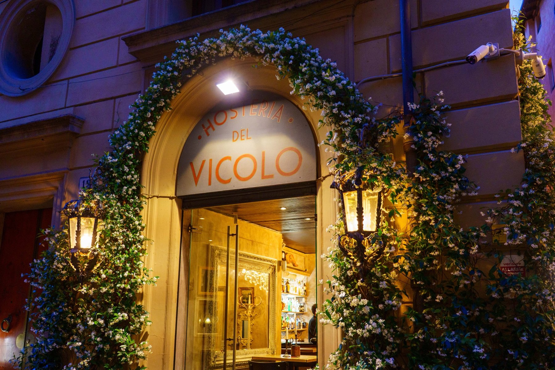 The flower-draped entrance to Hosteria del Vicolo in Bologna at night