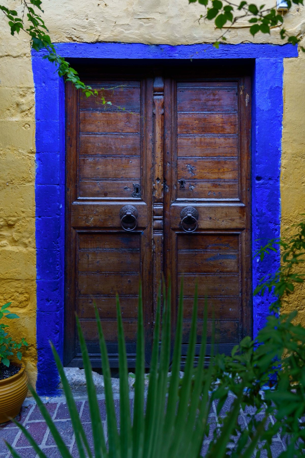 A weathered wooden door framed in blue in a Chania backstreet