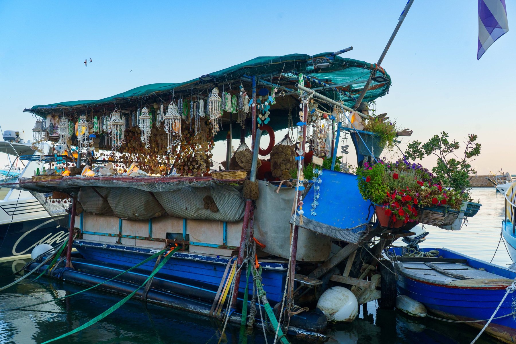 A trinket boat strung with shells and jewelry moored in Chania's harbor