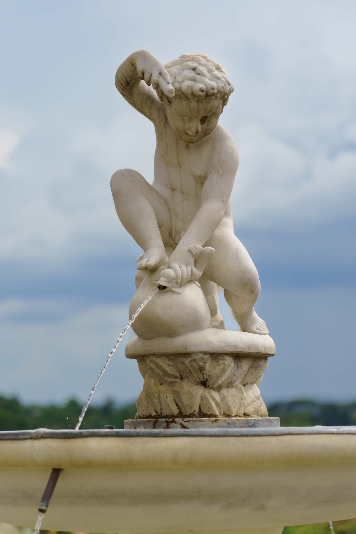A cherub fountain statue pouring water from a fish in the Giardino di Boboli