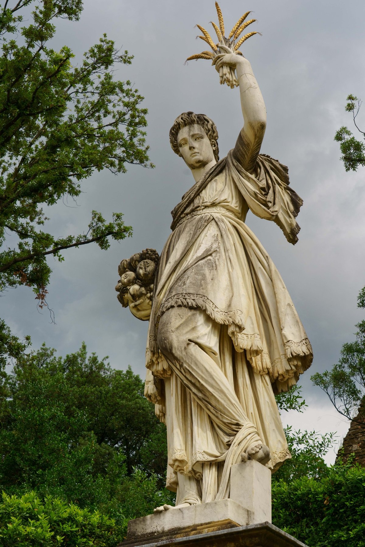A statue of Abundance holding gilded wheat sheaves and fruit in the Giardino di Boboli
