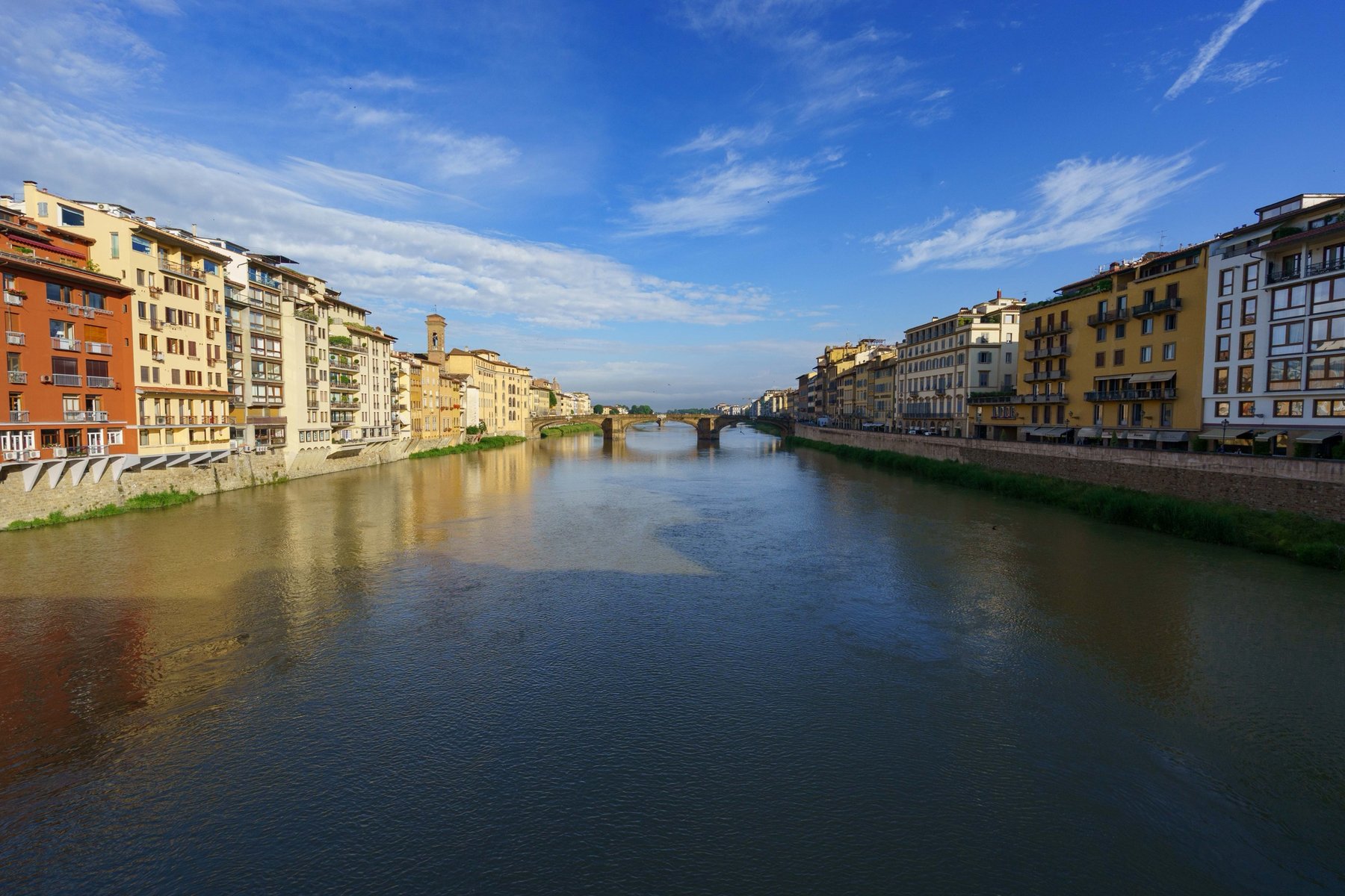 The Arno River lined with Florence's colorful buildings, a bridge in the distance