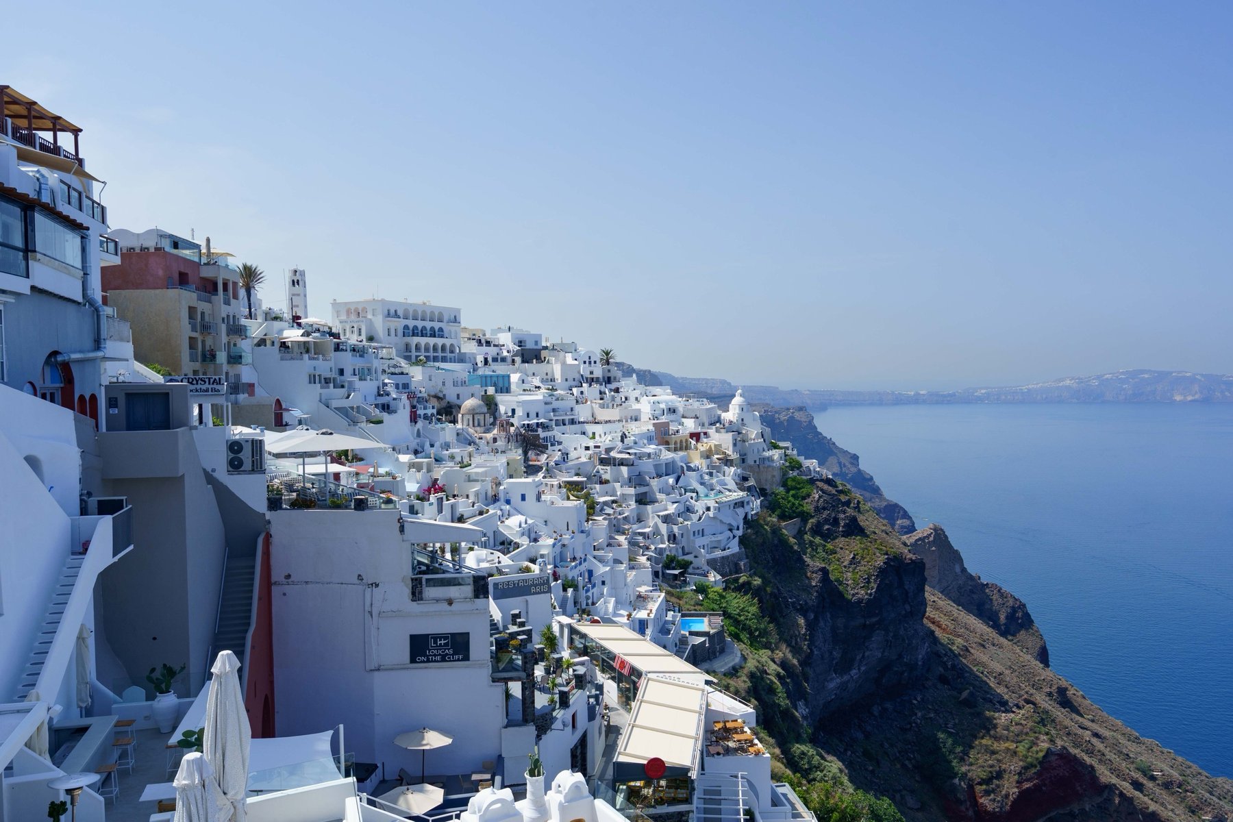 Whitewashed buildings clinging to the caldera cliffs while walking out of Fira, Santorini