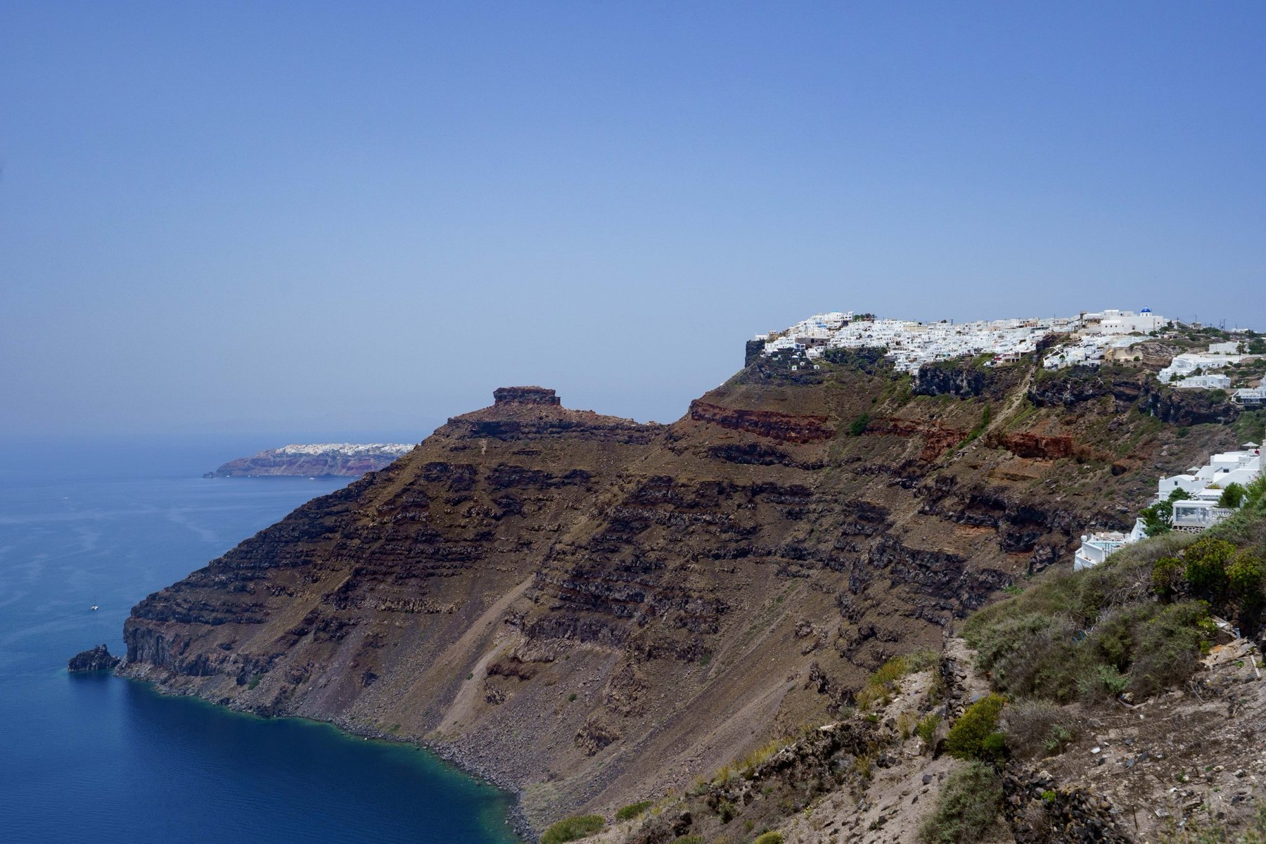 Imerovigli's clifftop village seen across the caldera in Santorini
