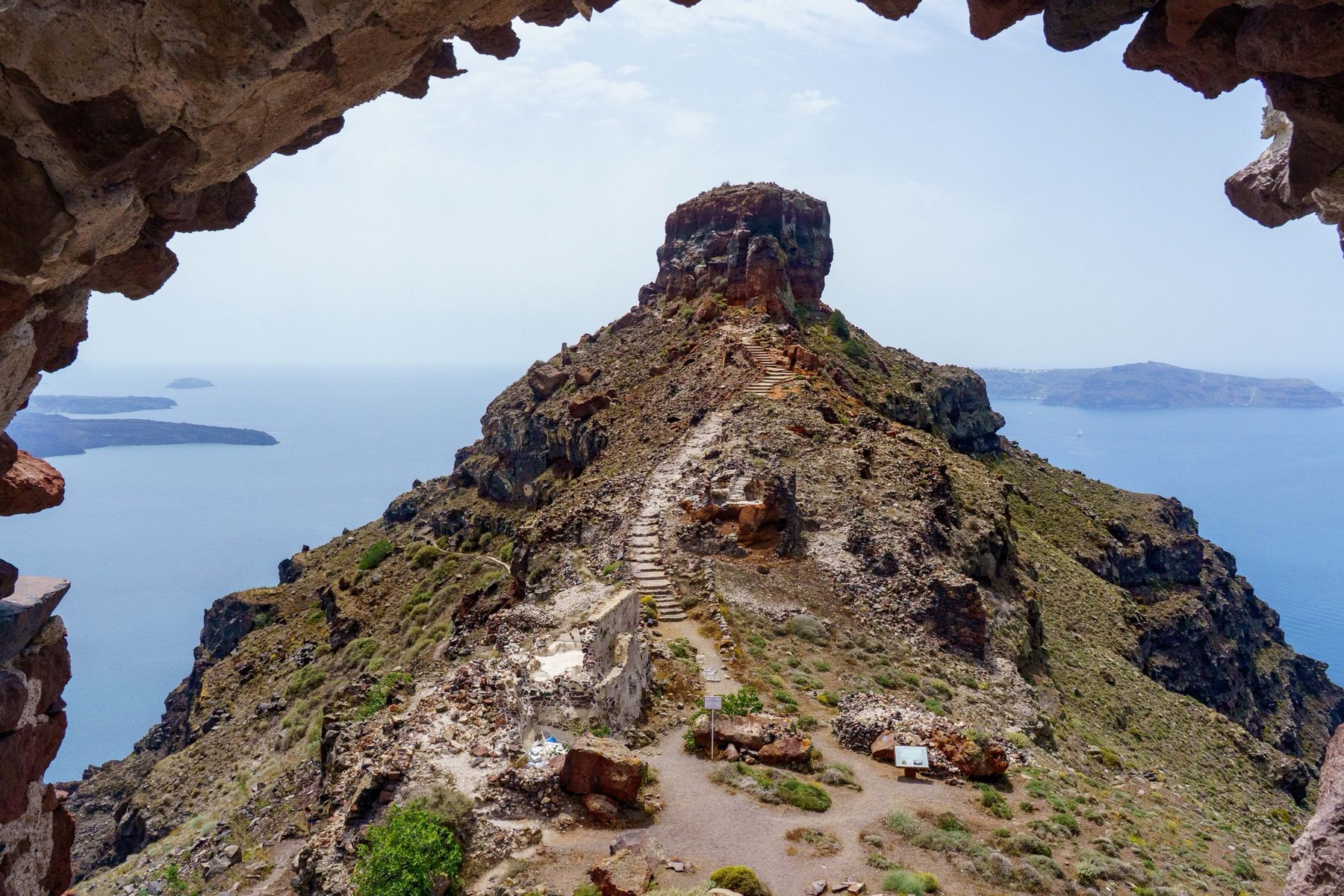 Skaros Rock framed through a cave opening along the caldera trail in Santorini
