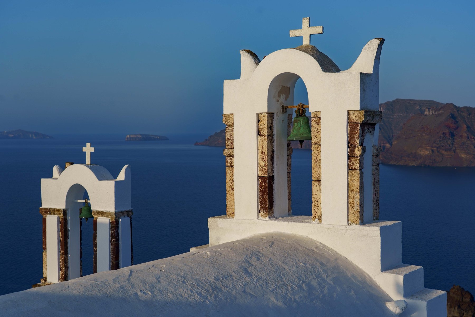 Twin white bell towers overlooking the caldera in Oia, Santorini