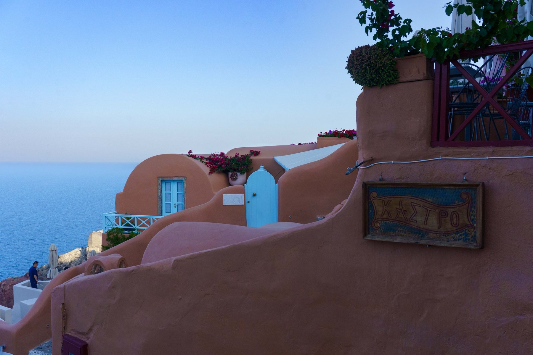 The coral walls and blue doors of Kastro, Oia's sunset viewpoint in Santorini