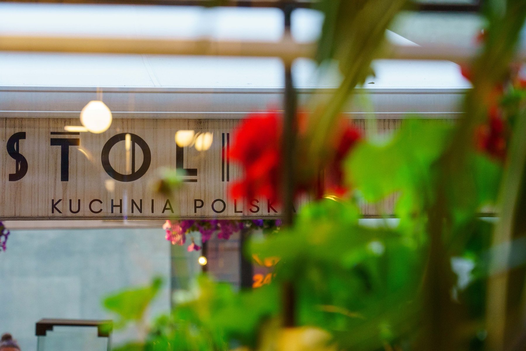 The sign for Stoli, a Polish kitchen restaurant, framed by geraniums