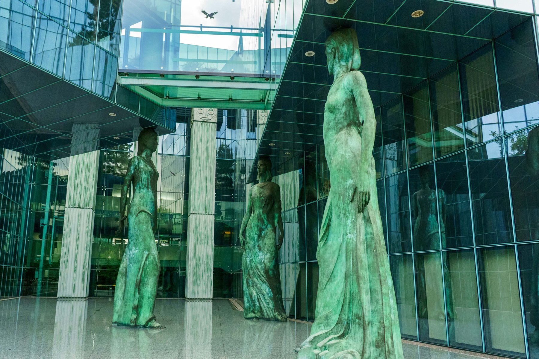 Weathered bronze figures outside a glass building near the Supreme Court in Warsaw