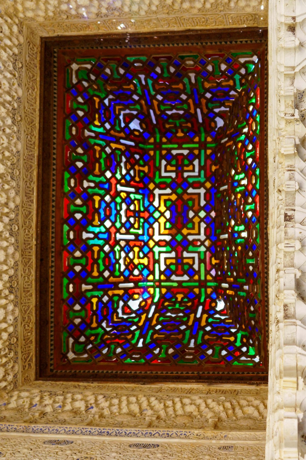 A colorful geometric stained glass window inside the Alhambra