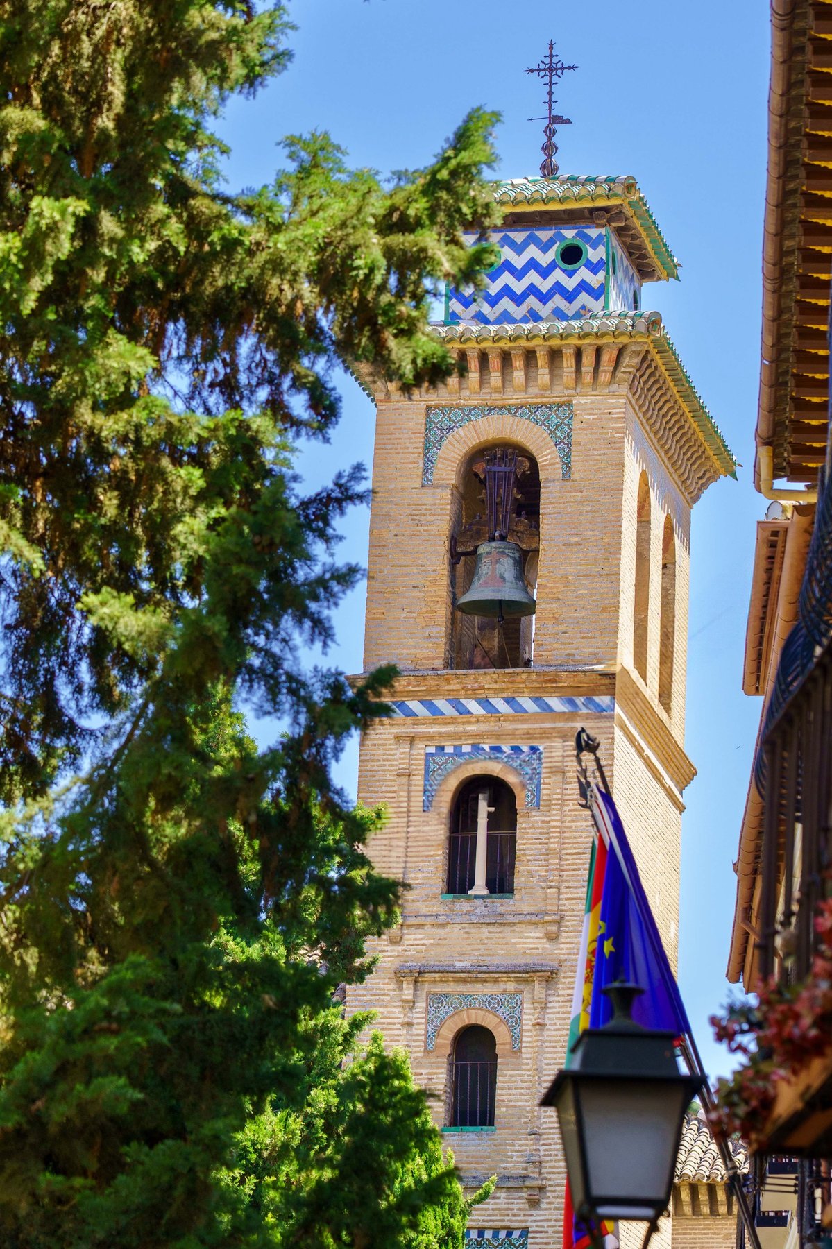 A tiled Mudéjar-style bell tower rising above trees in Granada