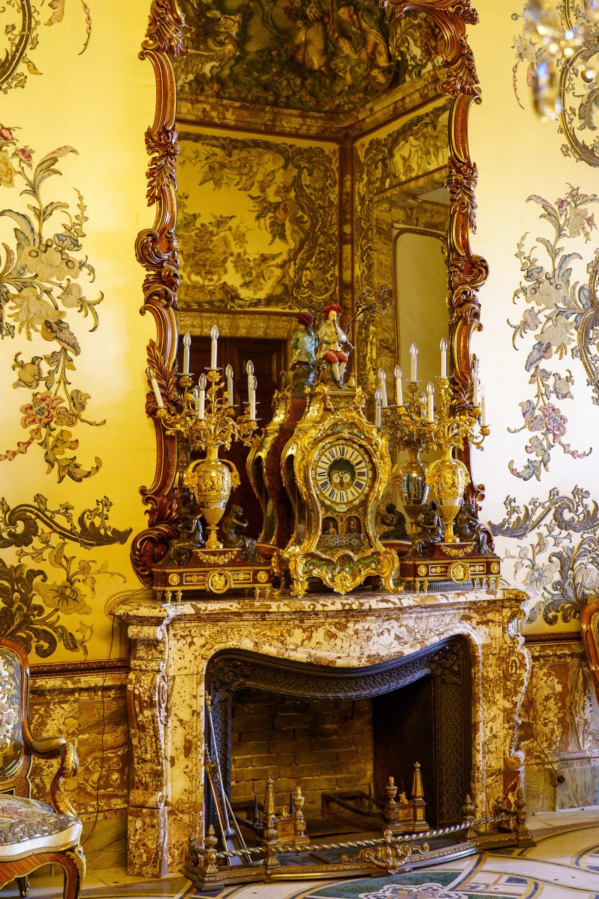 A gilded clock and candelabra above a marble fireplace in the Royal Palace