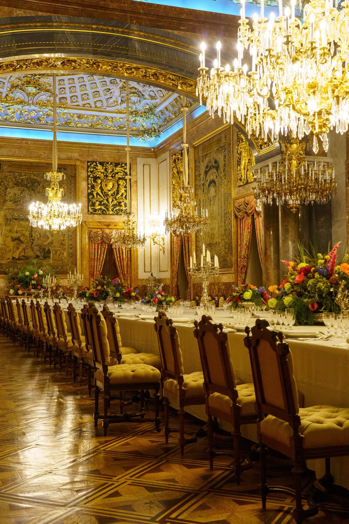 The banquet hall of the Royal Palace set with chandeliers and flowers for a formal dinner