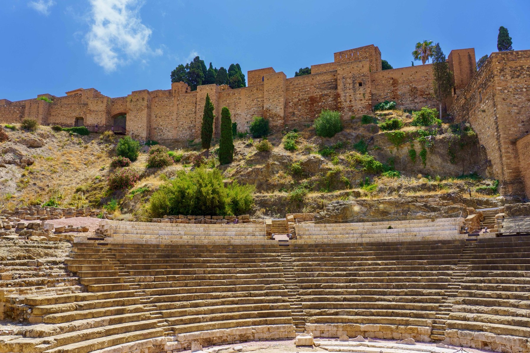 The Roman Theatre of Málaga with the Alcazaba's fortress walls rising behind it