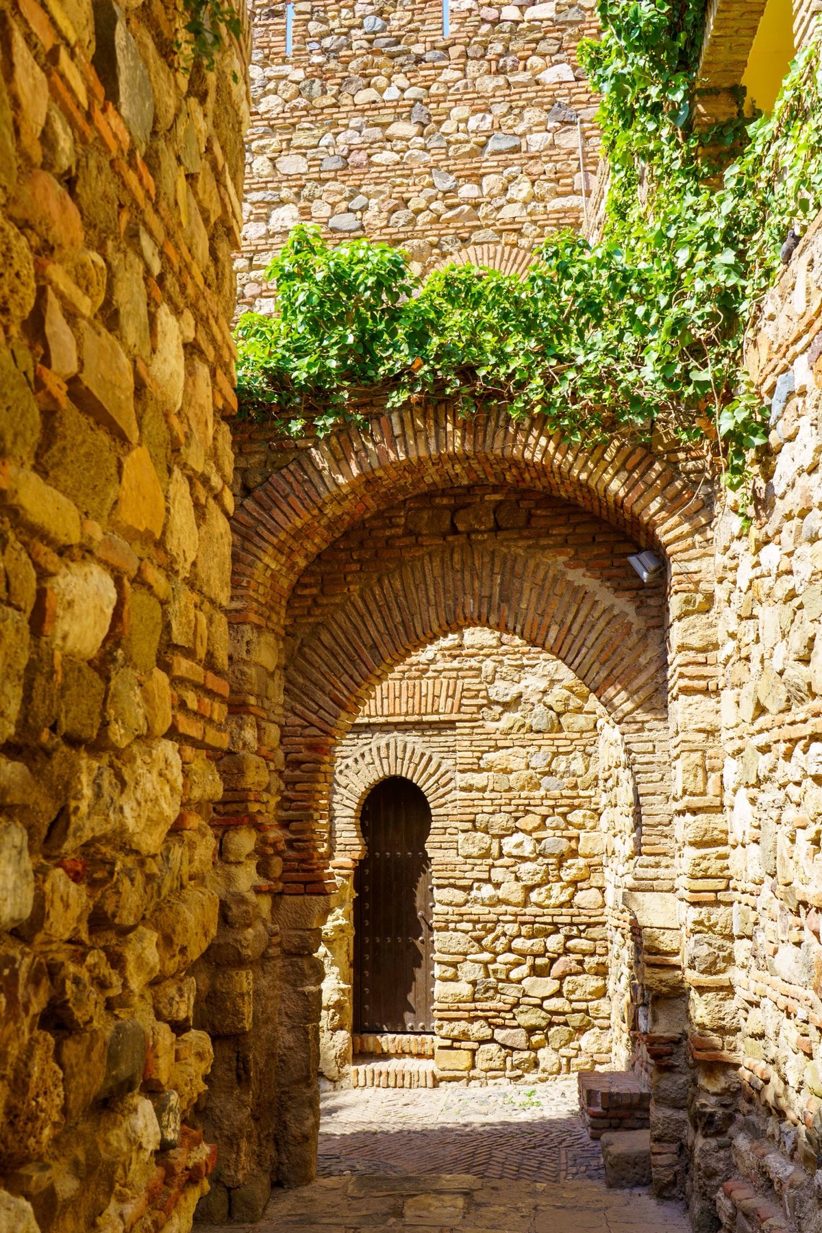 A horseshoe-arched doorway along a stone passage within the Alcazaba
