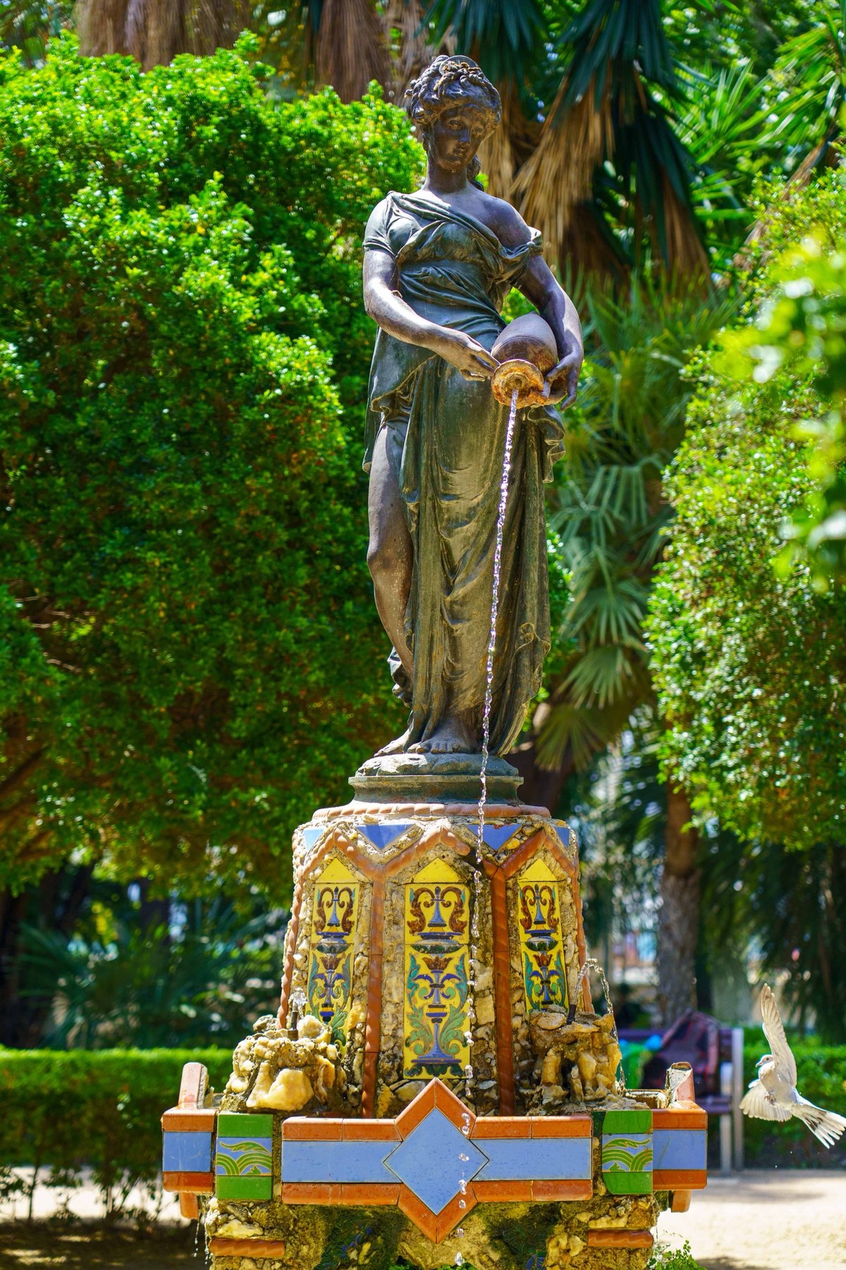 A bronze fountain statue of a woman pouring water from a jug in Parque de Málaga