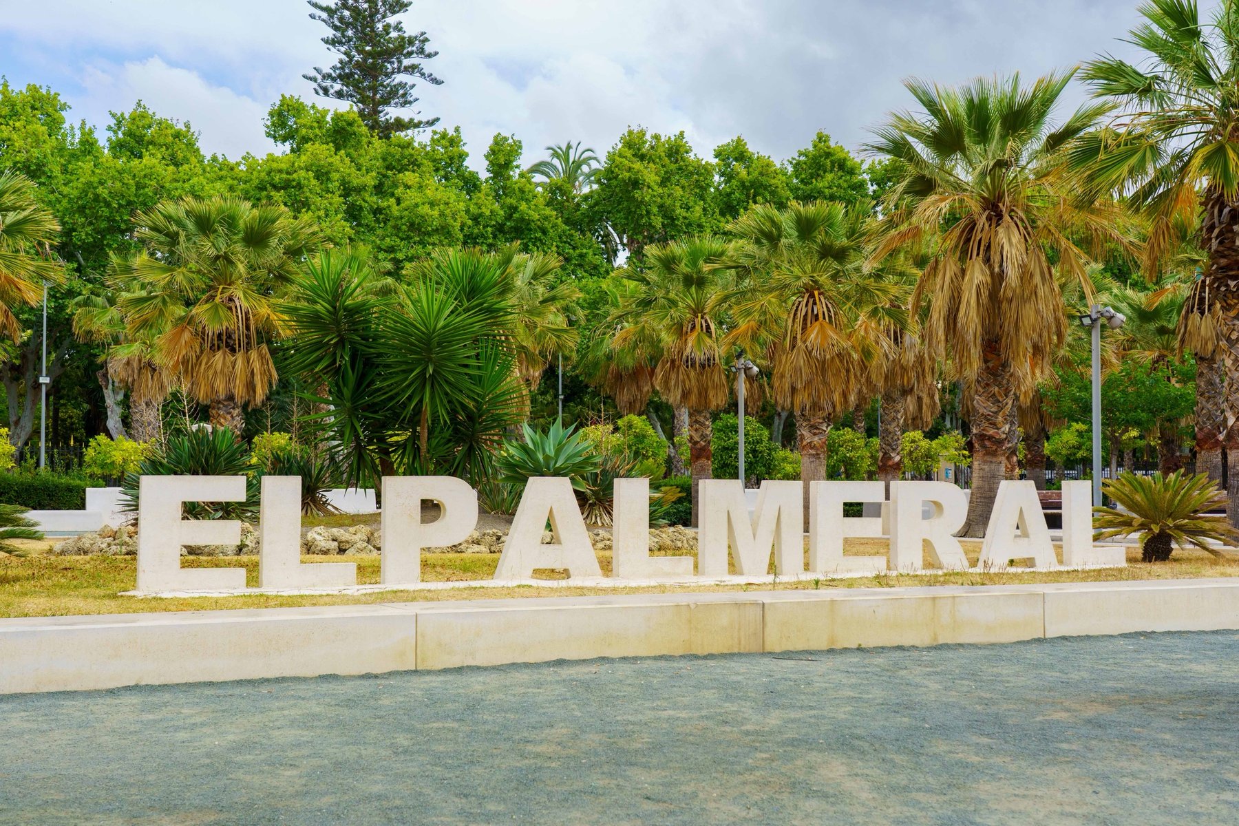 Large block letters spelling El Palmeral along Málaga's waterfront promenade