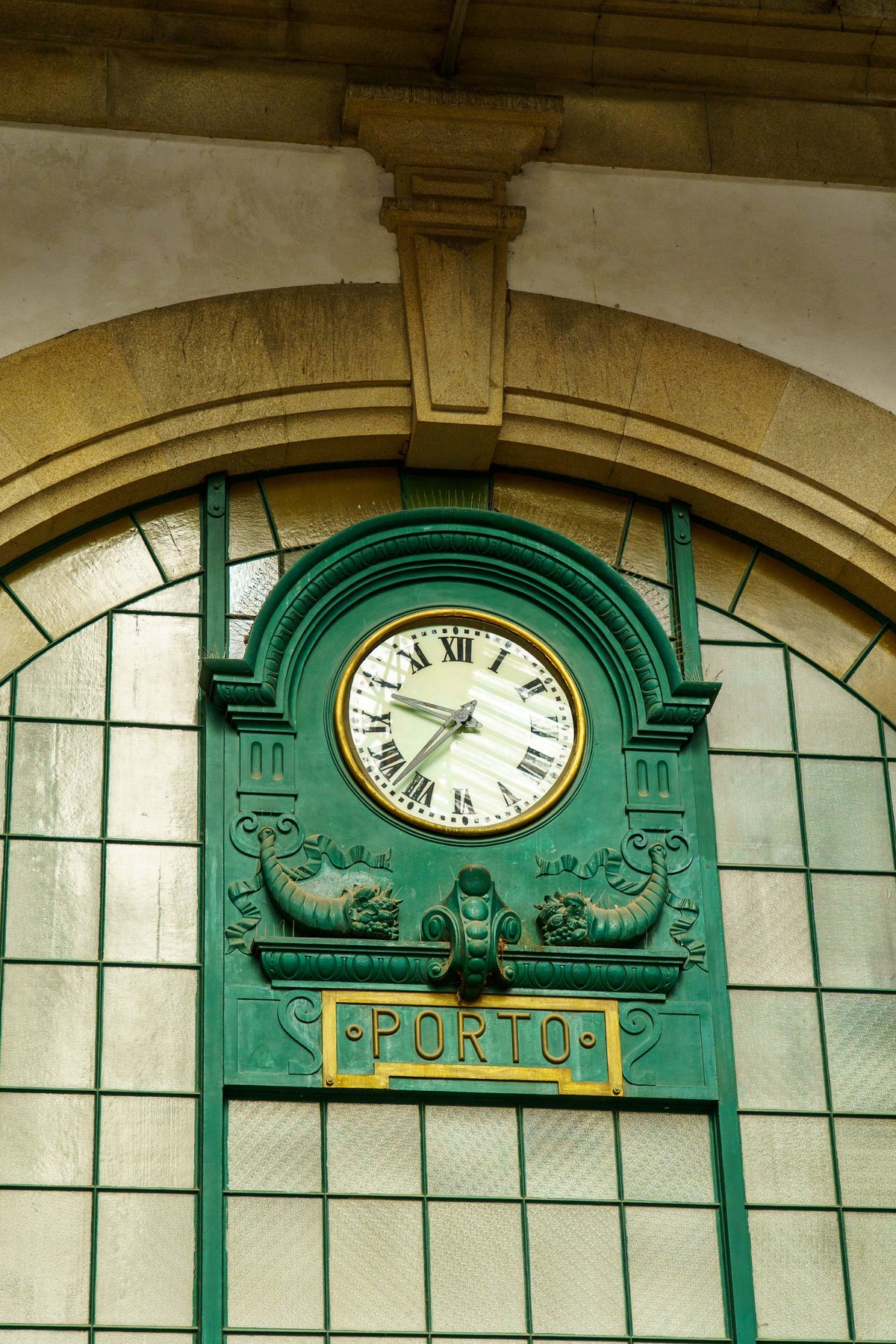 An ornate green clock labeled Porto inside São Bento Station