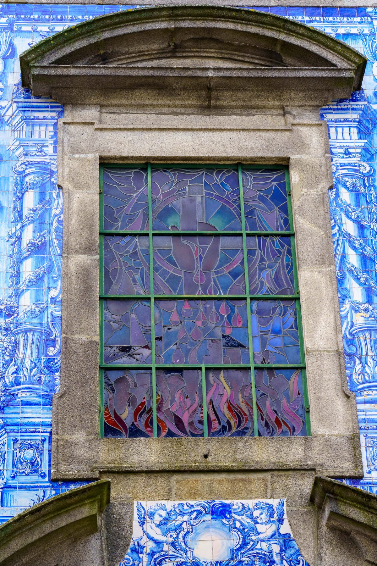 A modern stained glass window set into the tiled facade of Capela das Almas