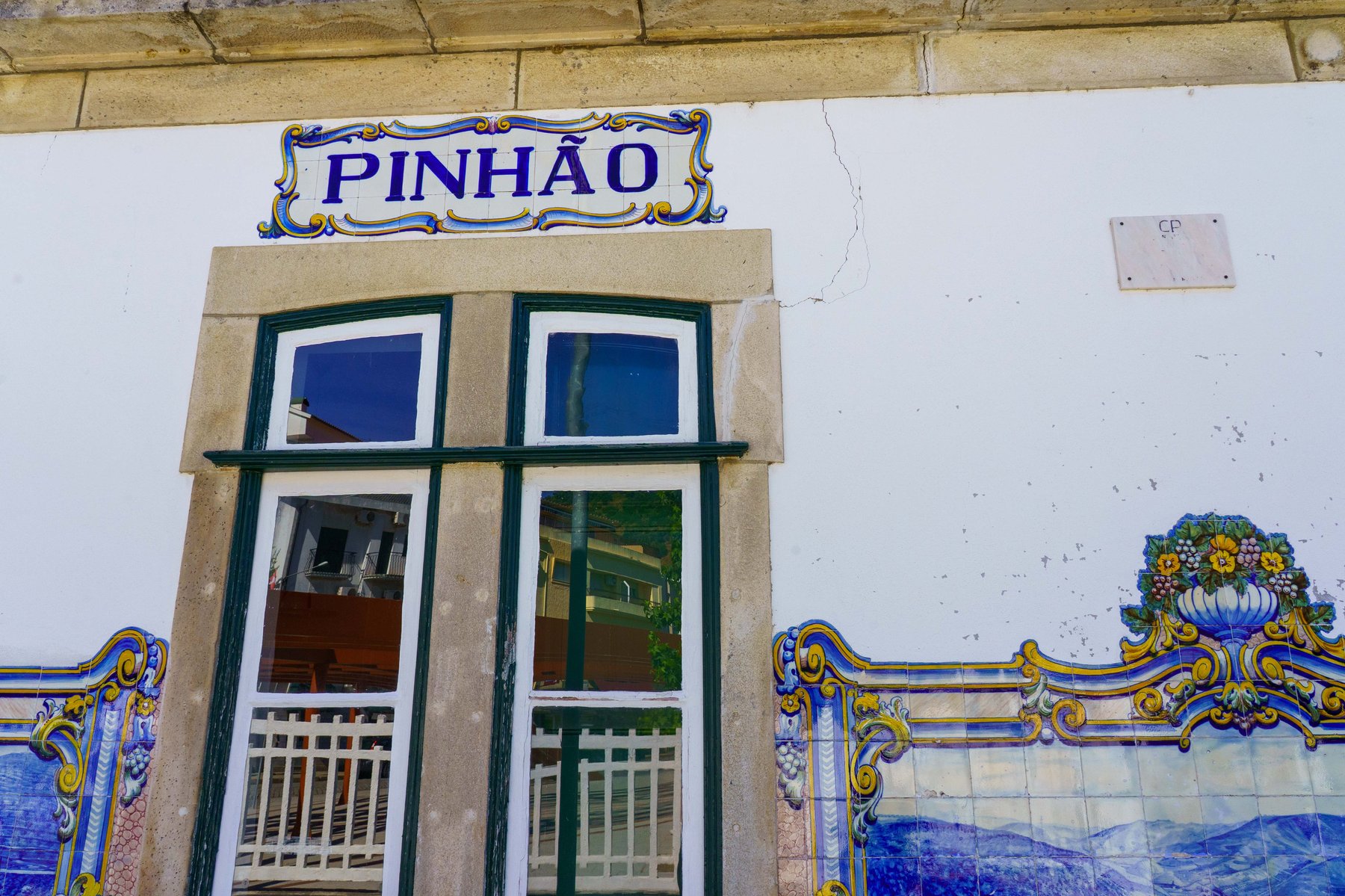 An azulejo tile sign reading Pinhao above a station doorway