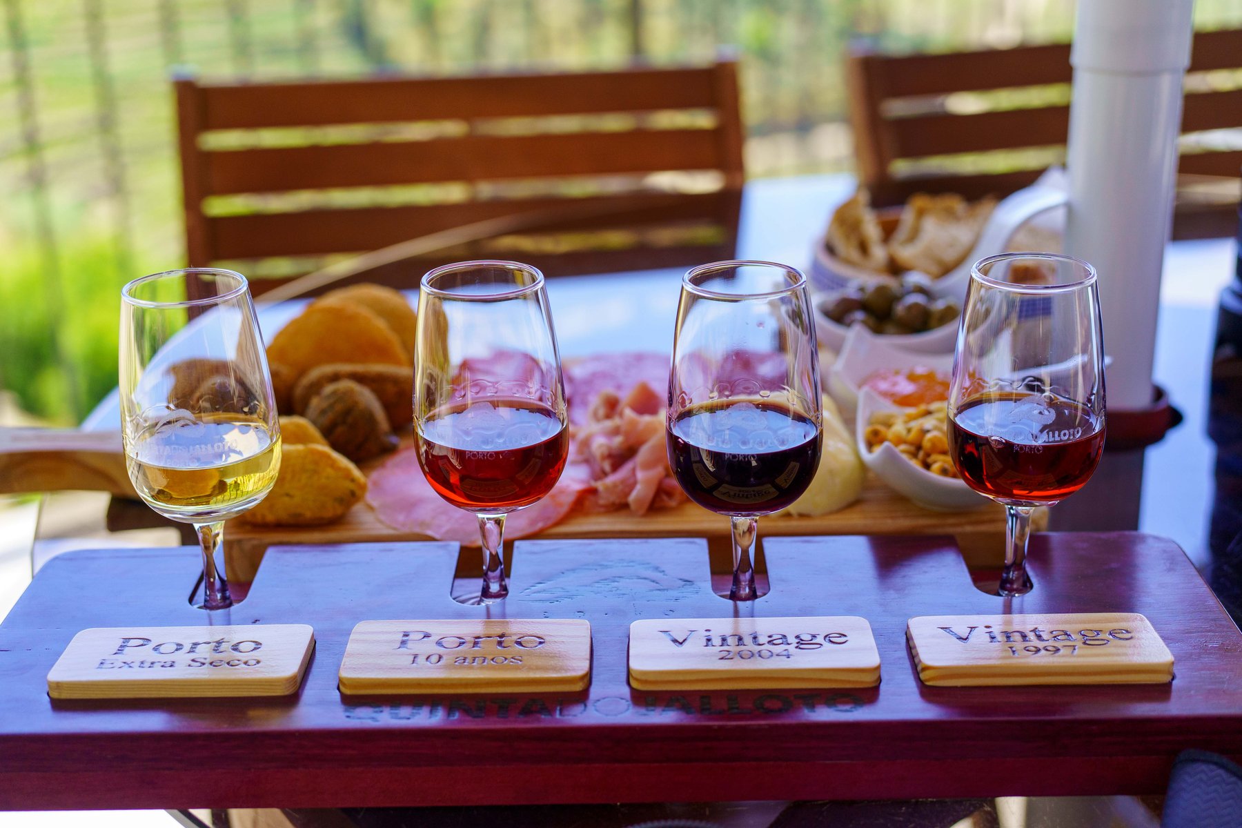 A flight of four port glasses labeled Extra Seco, 10 anos, and two vintages at Quinta do Jalloto