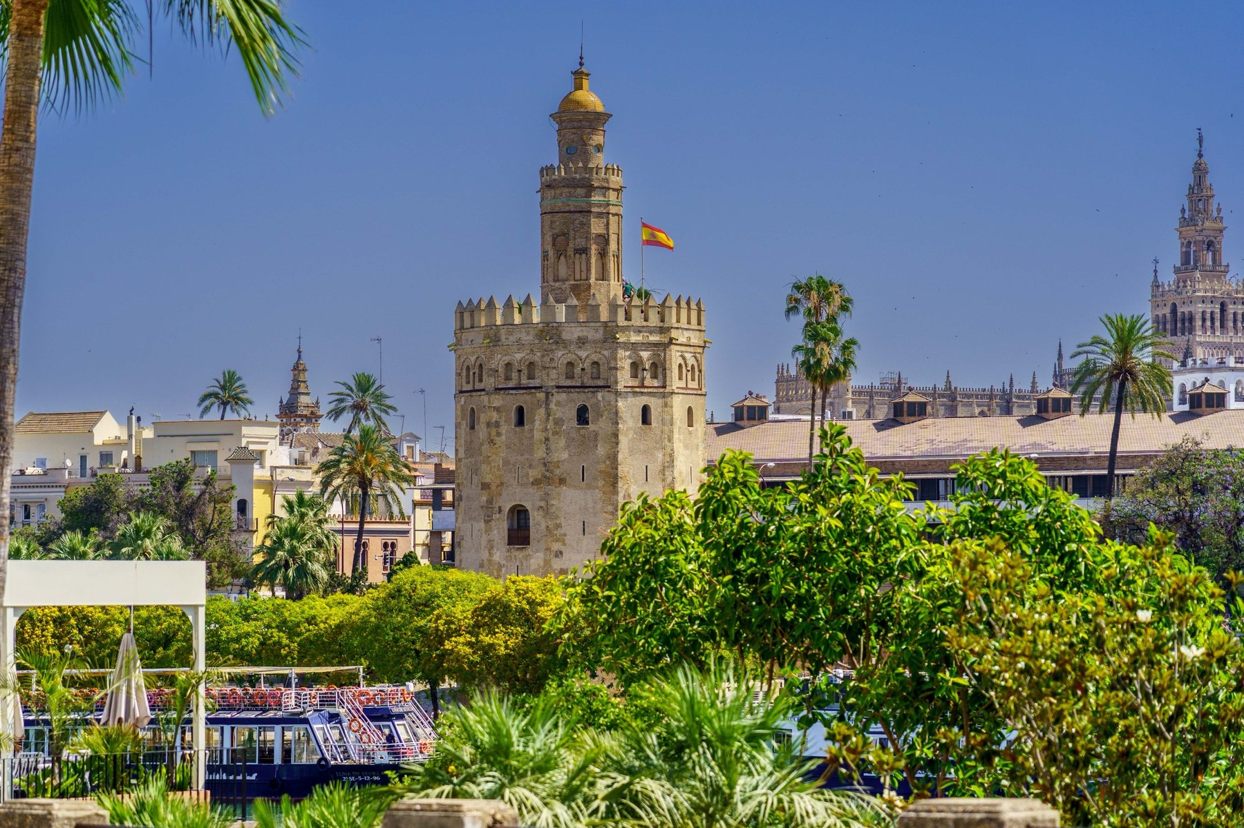 The Torre del Oro beside the Guadalquivir River, framed by palm trees