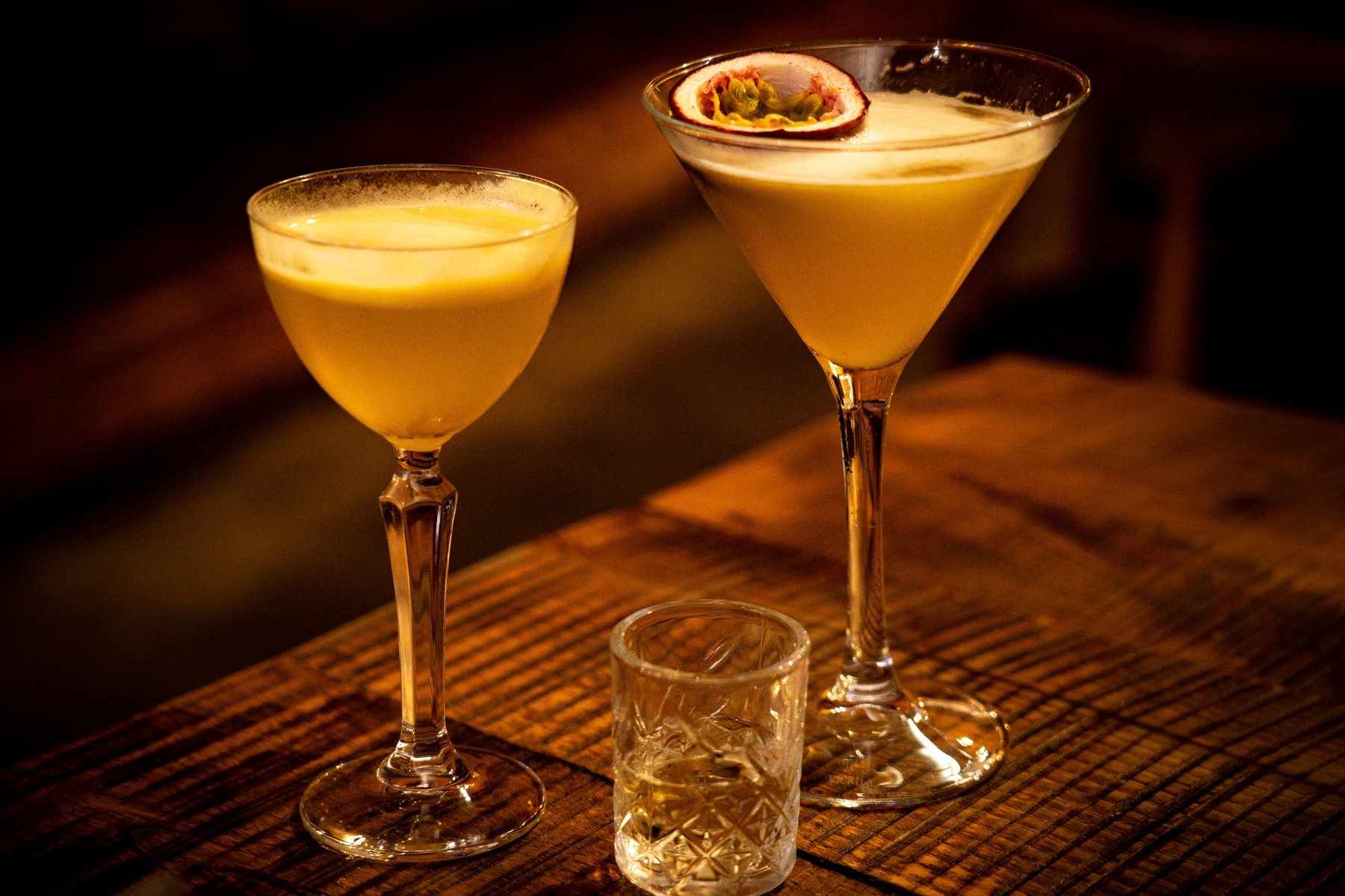 Two passionfruit cocktails on a wooden table
